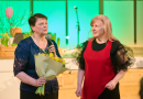 Divas sievietes uz skatuves ar ziediem rokās