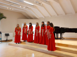 Vokālā ansambļa MOZAĪKA dalībnieces koši sarkanos tērpos uz Ķekavas Mūzikas skolas skatuves