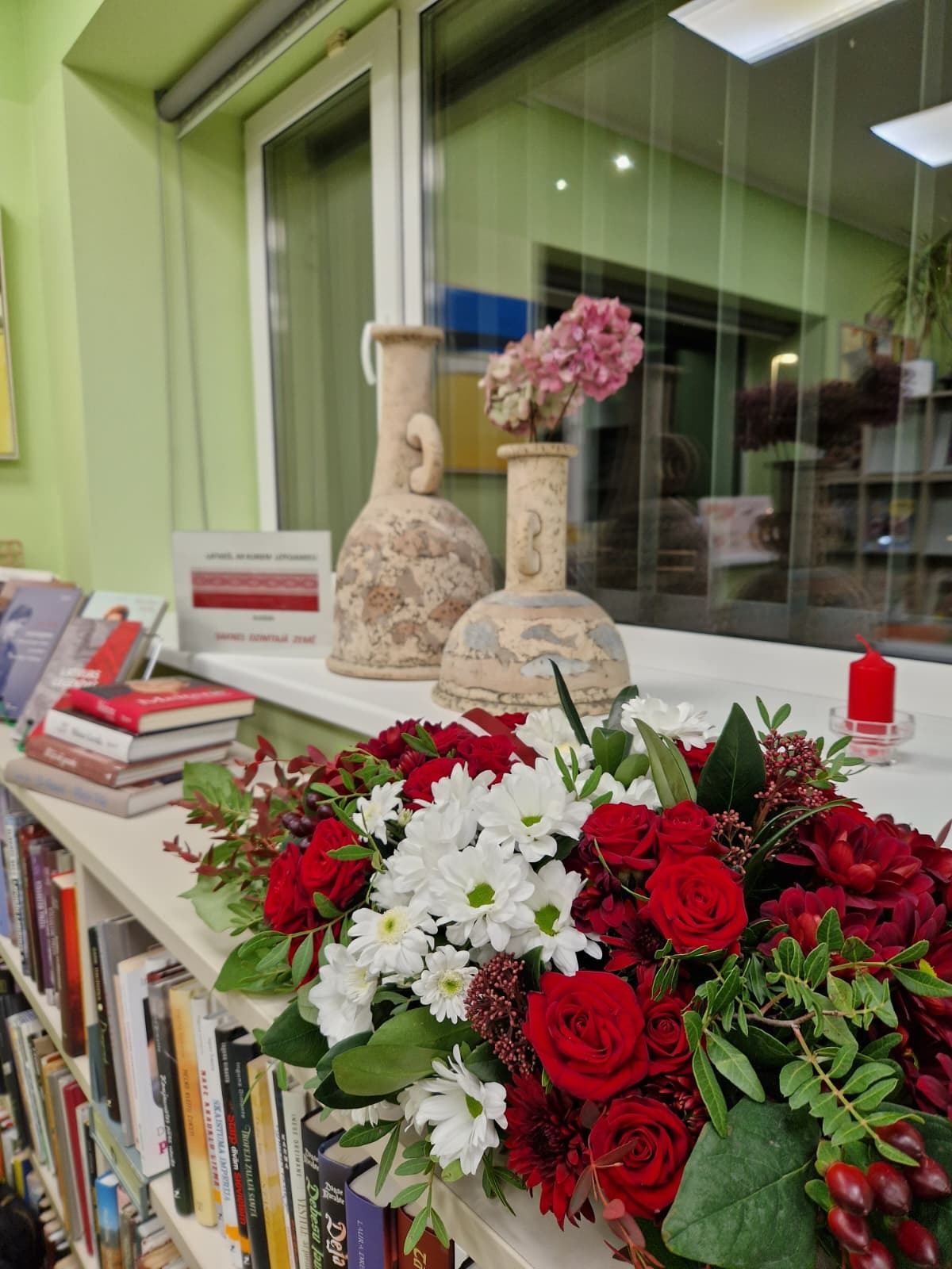 Ziedu kompozīcija, grāmatas un vāzes uz palodzes