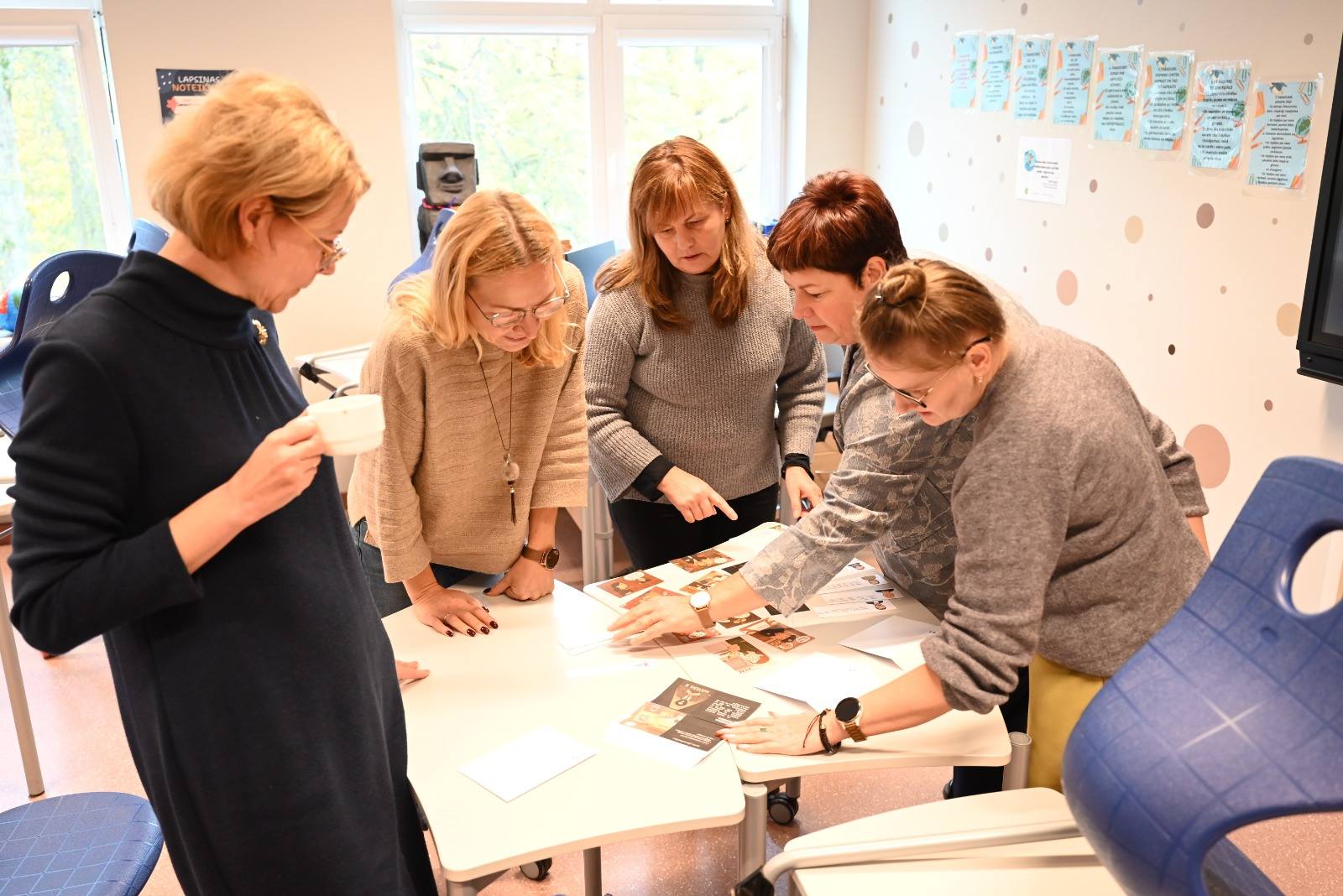 Cilvēki nostājušies apkārt galdam