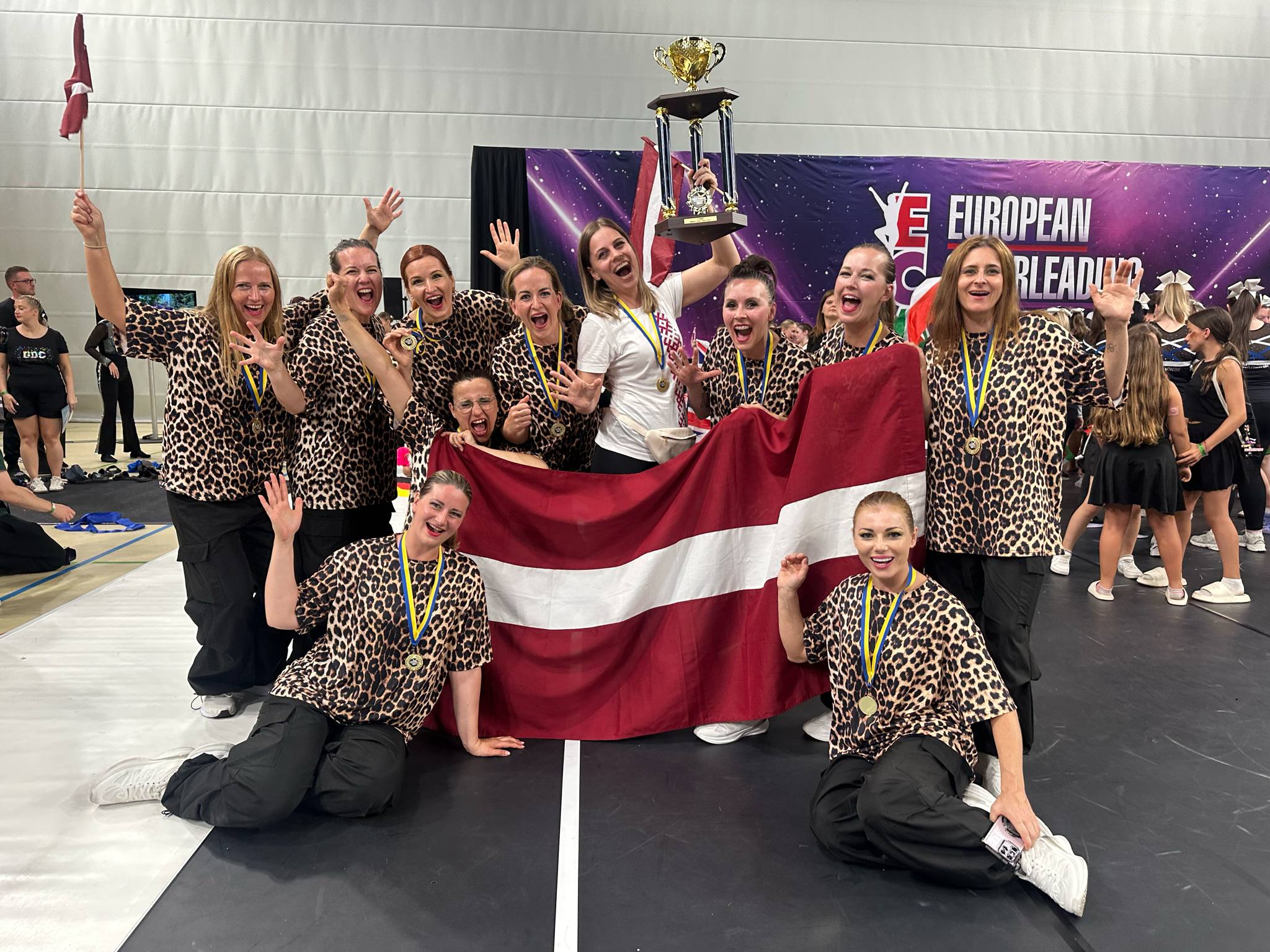 Sievietes leoparda kreklos un lielu kausu rokās