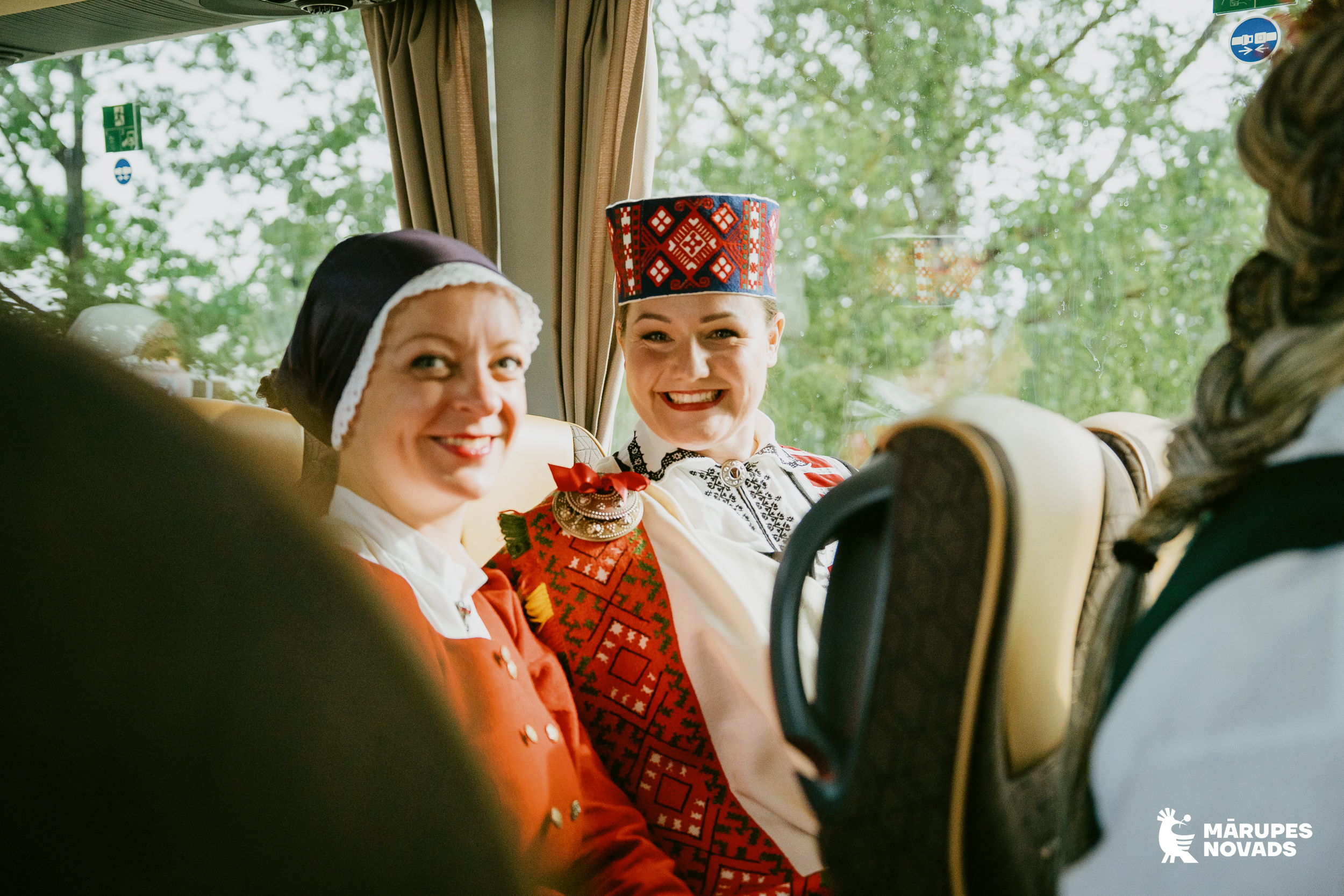 Divas sievietes tautas tērpos sēž autobusā