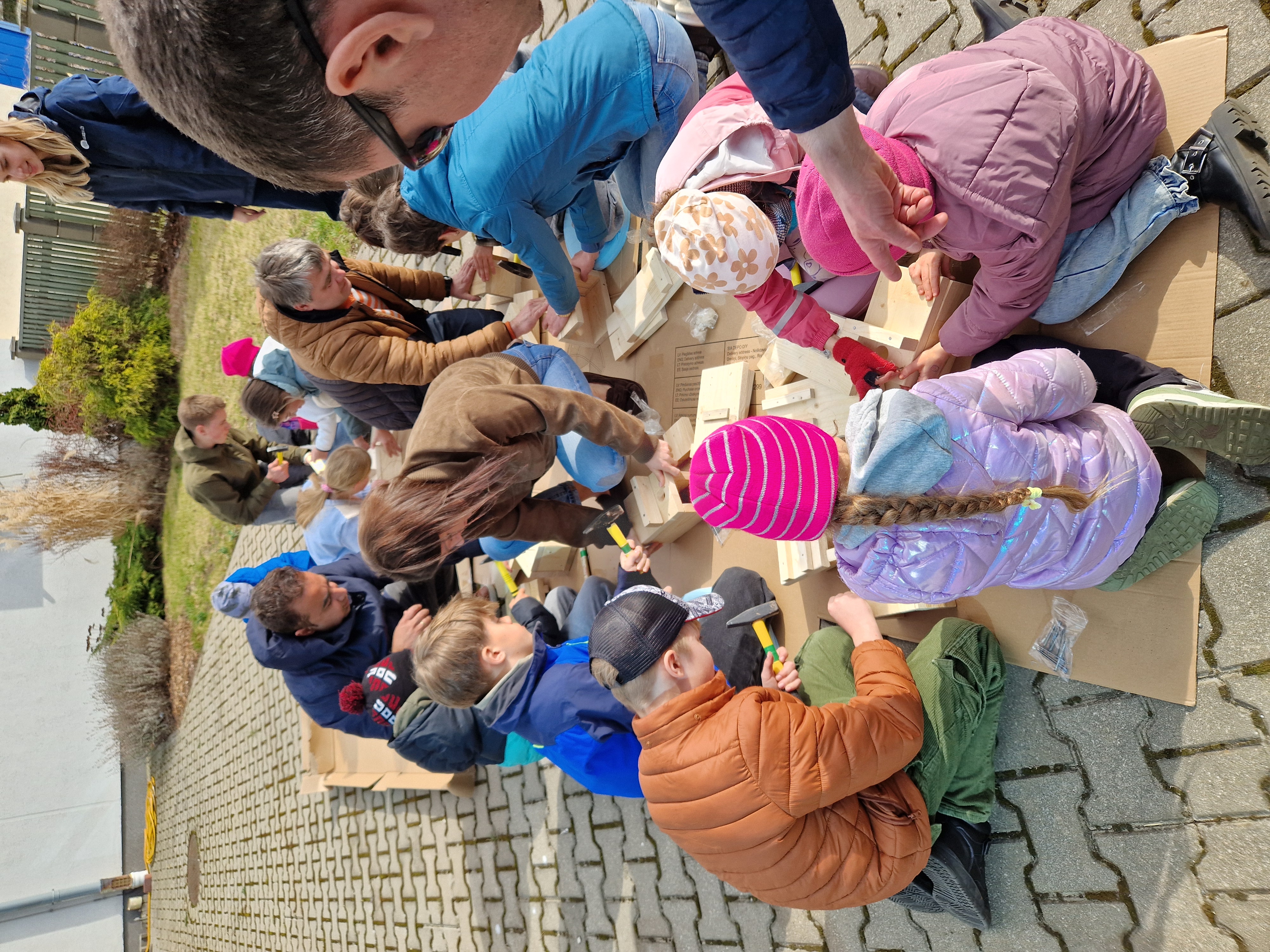 cilvēku grupa brīvdabā veido putnu būrus