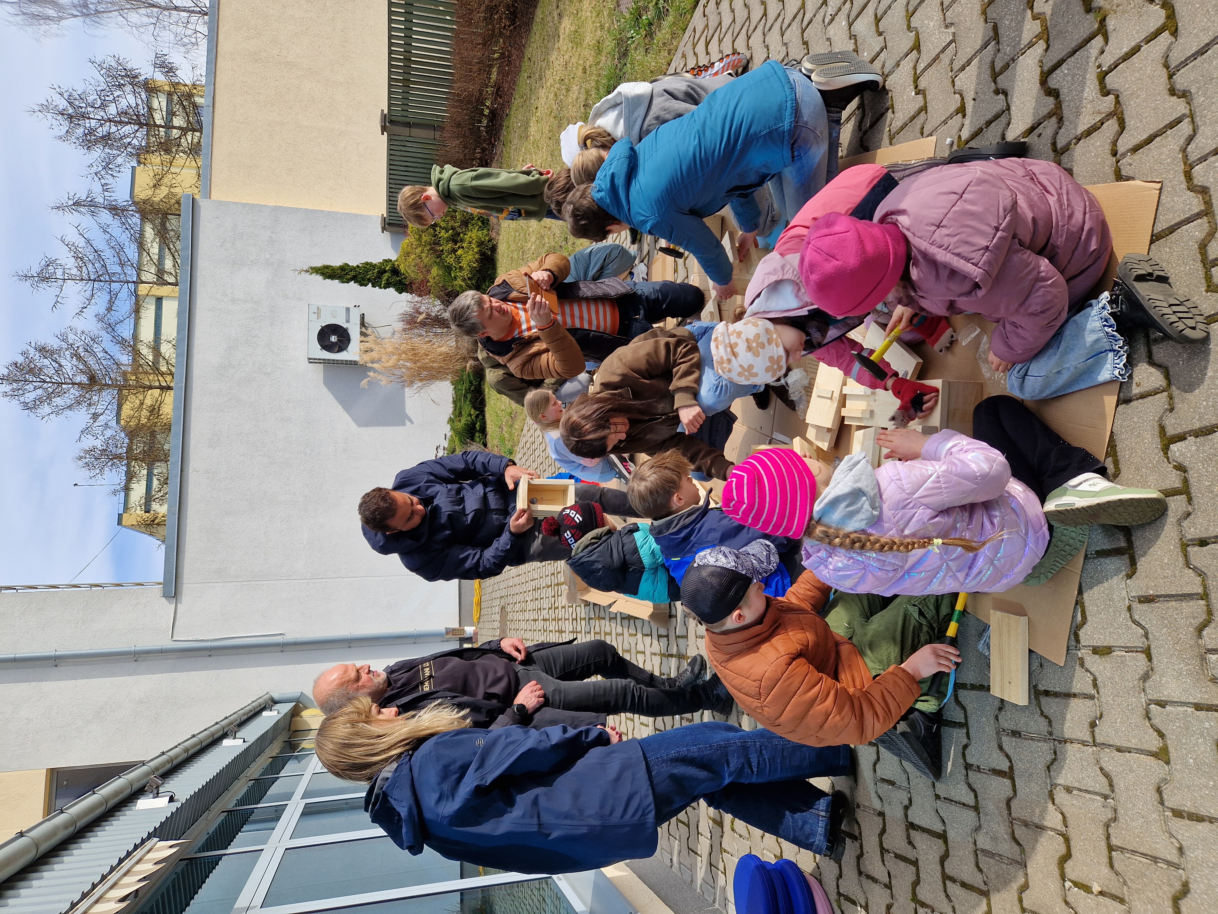 cilvēku grupa brīvdabā veido putnu būrus