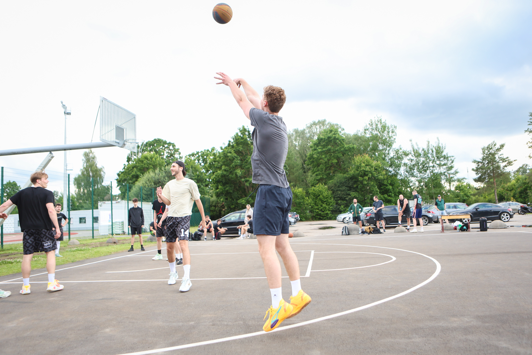 Puiši spēlē basketbola uz asfalta seguma