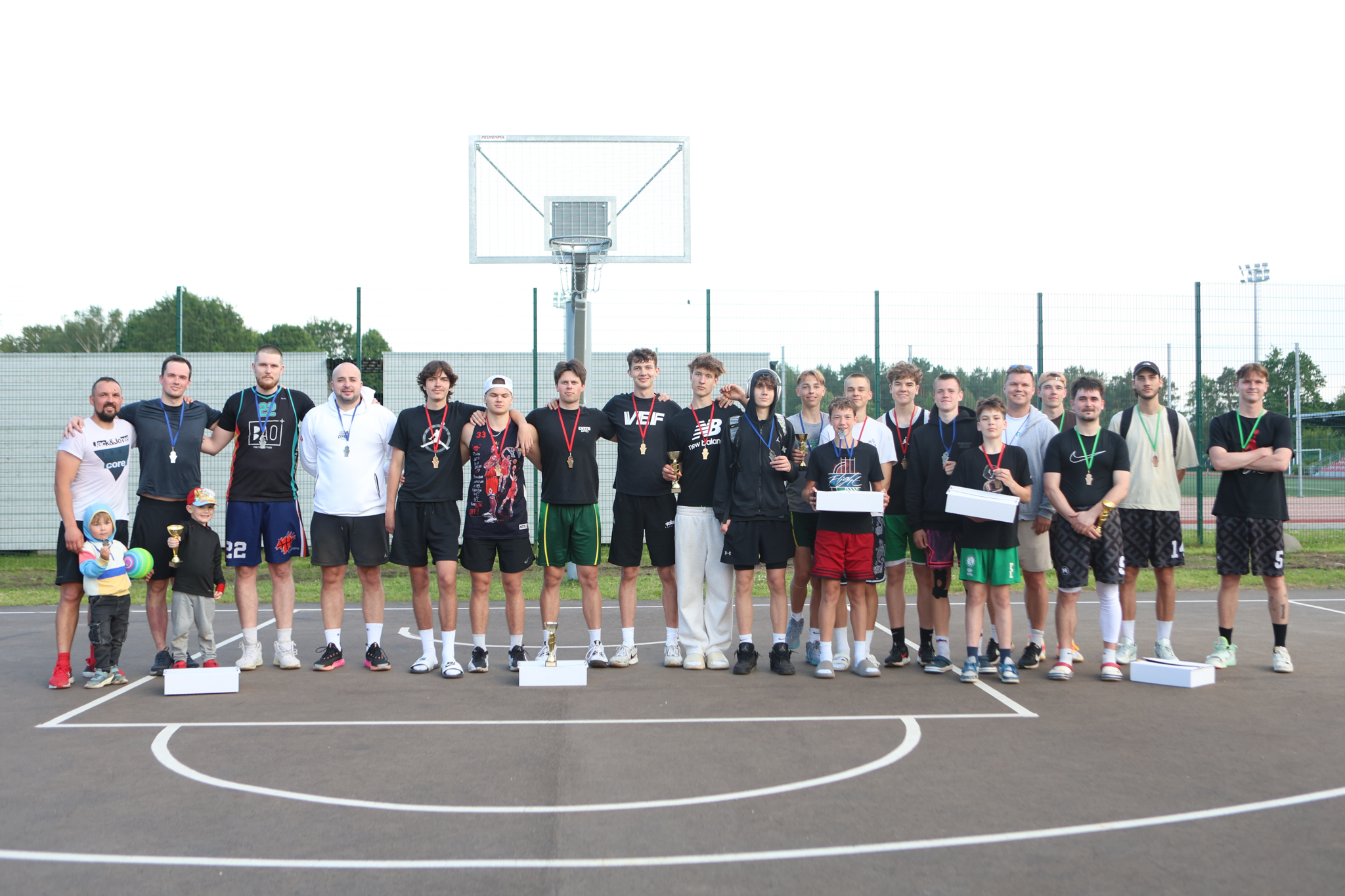 Puiši spēlē basketbola uz asfalta seguma