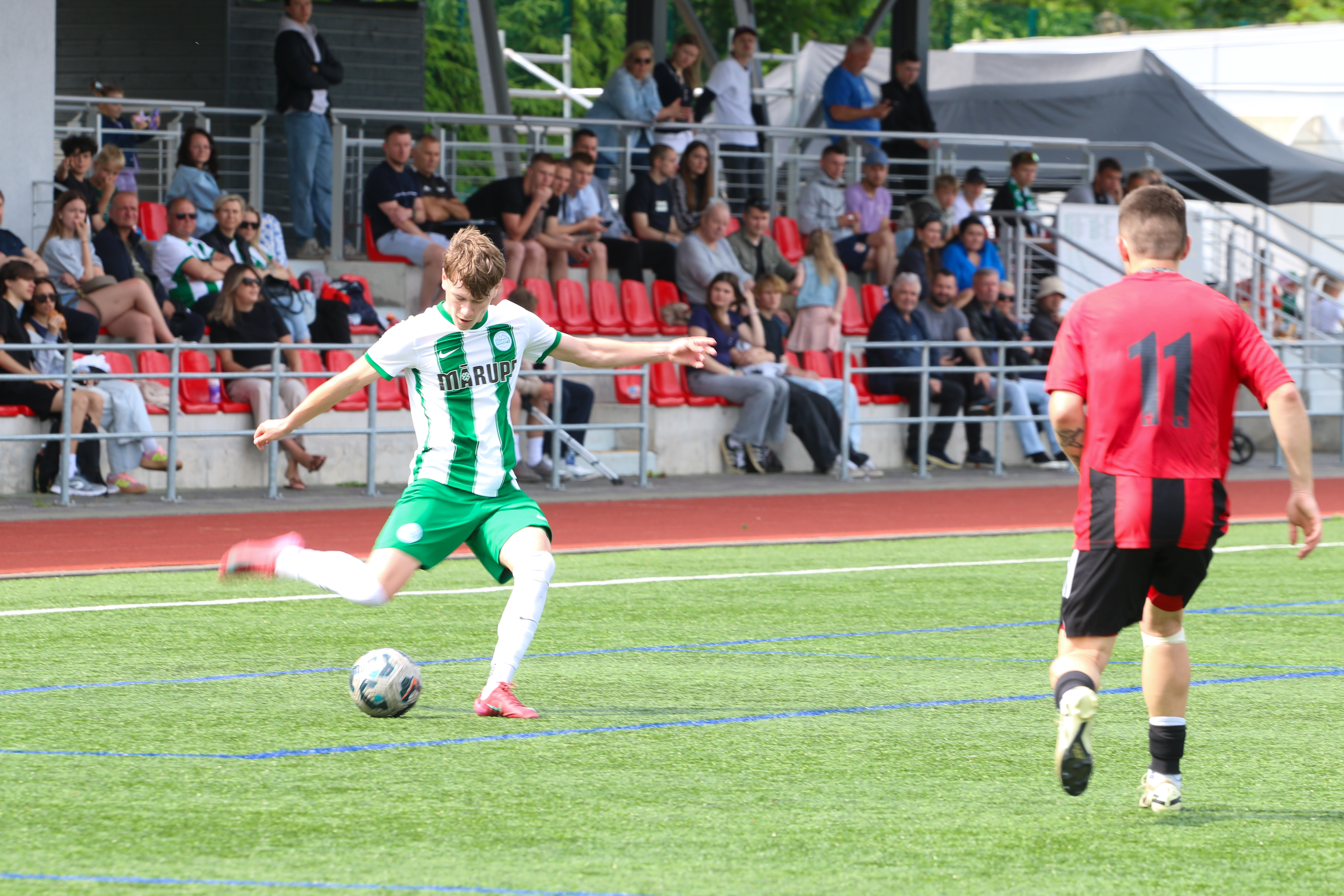 Futbolisti spēlē bumbu uz zālāja