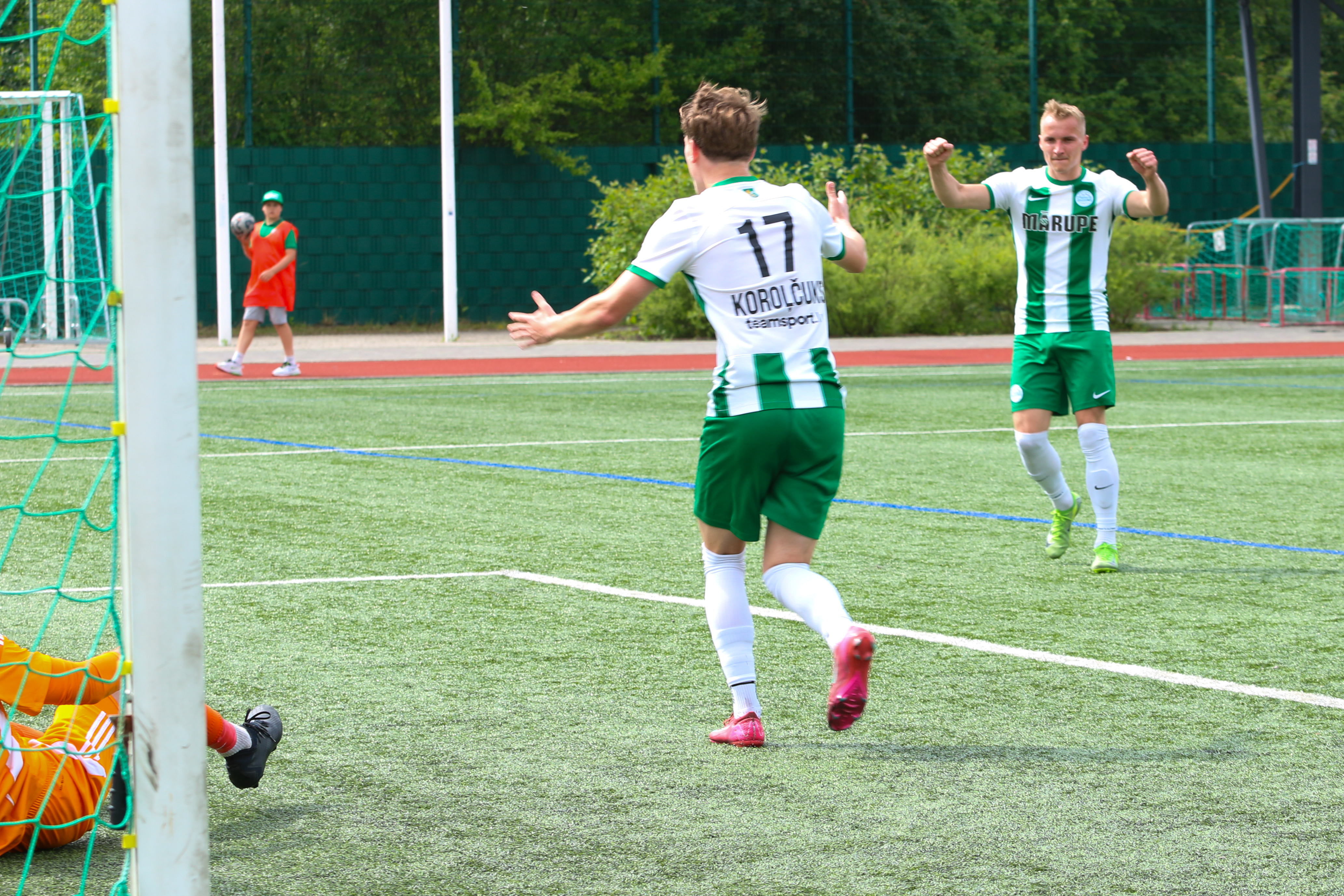 Futbolisti spēlē bumbu uz zālāja