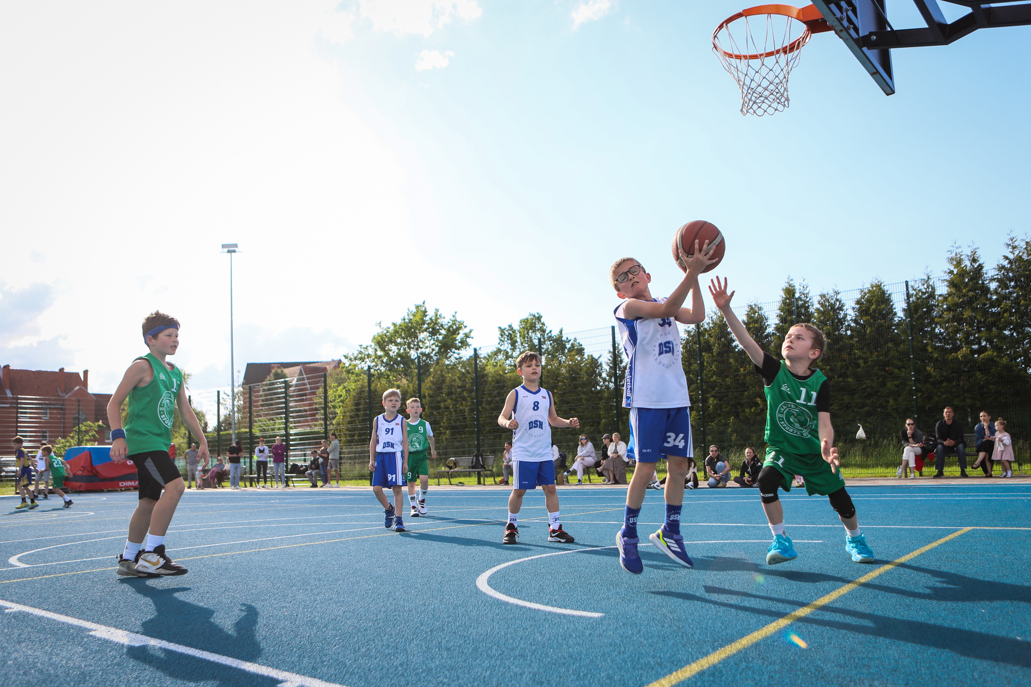puiši spēlē basketbola uz zila seguma sporta laukumā