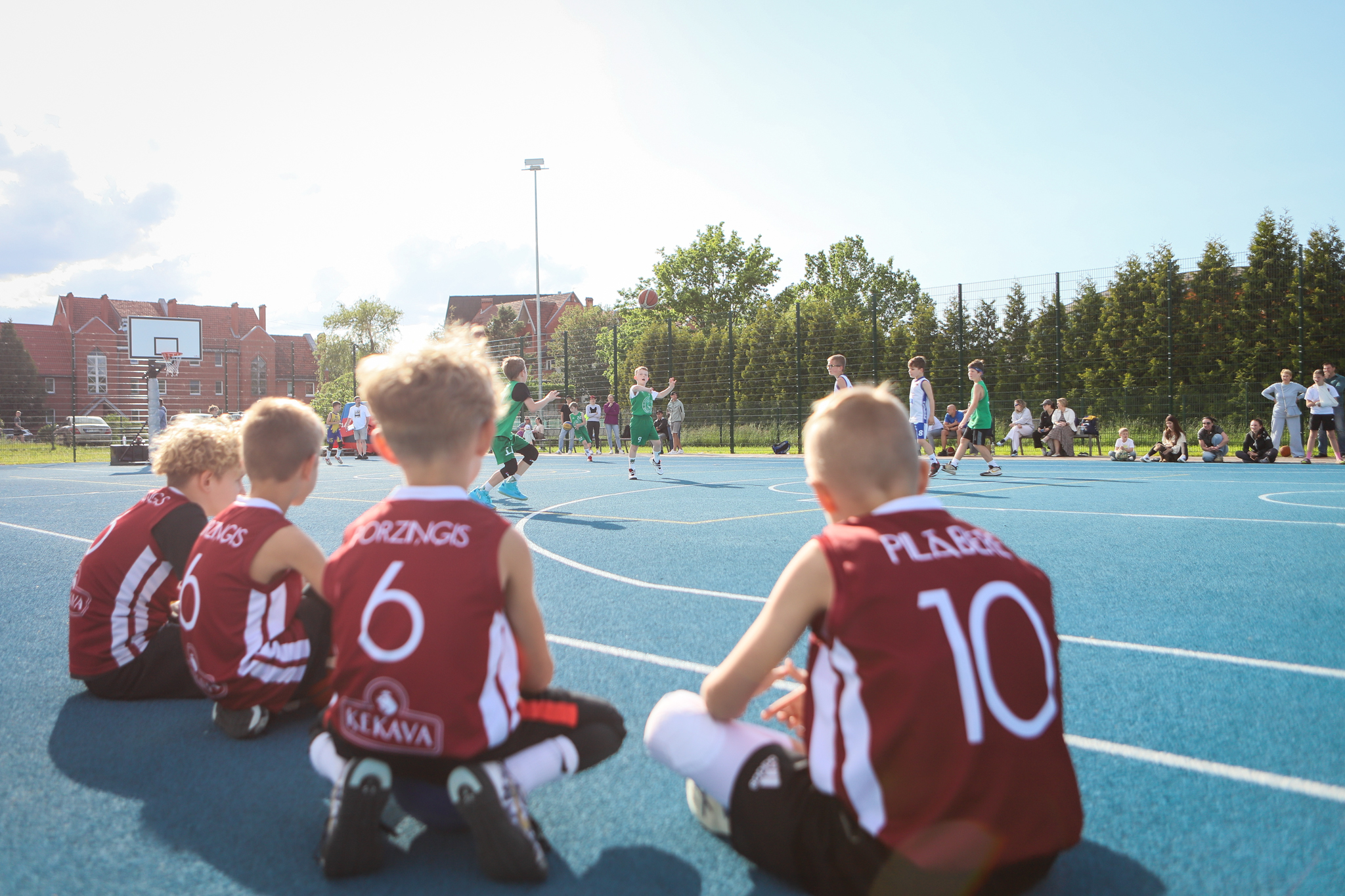 puiši spēlē basketbola uz zila seguma sporta laukumā