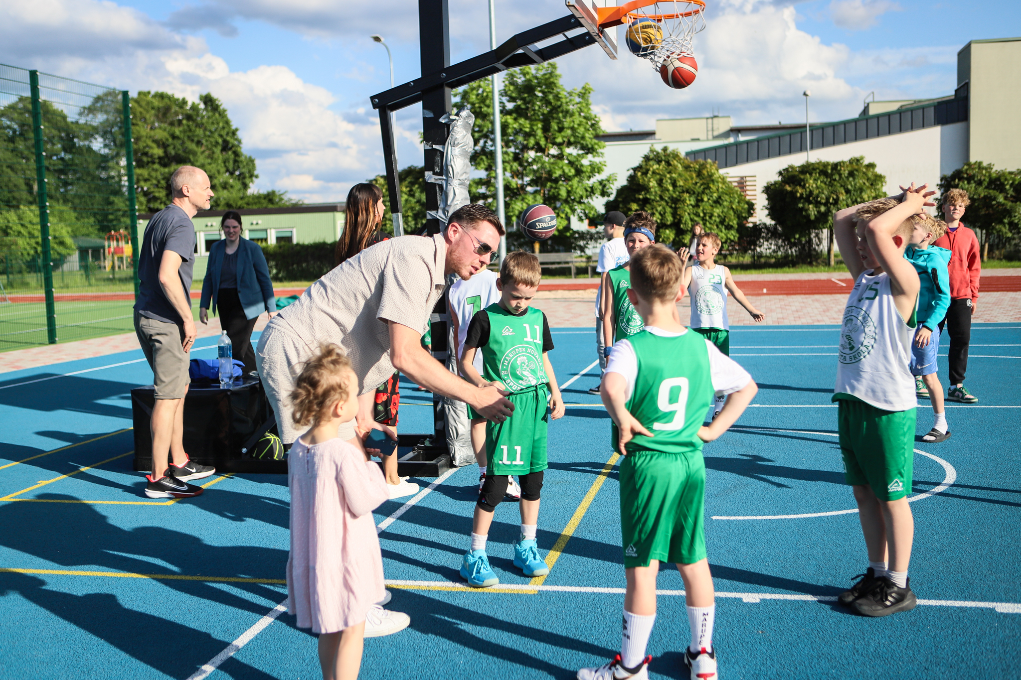 puiši spēlē basketbola uz zila seguma sporta laukumā