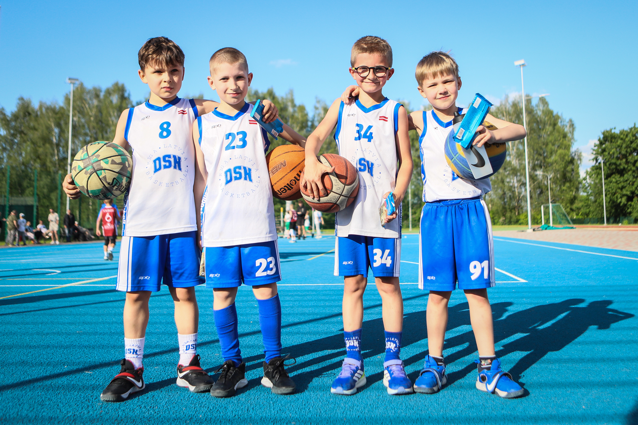 puiši spēlē basketbola uz zila seguma sporta laukumā