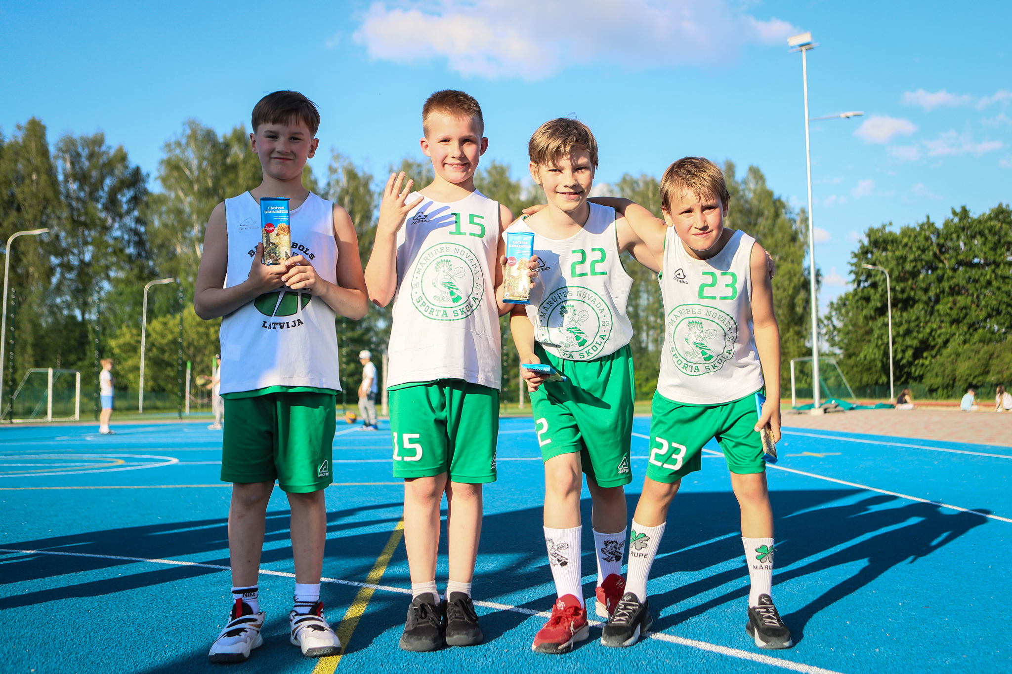 puiši spēlē basketbola uz zila seguma sporta laukumā