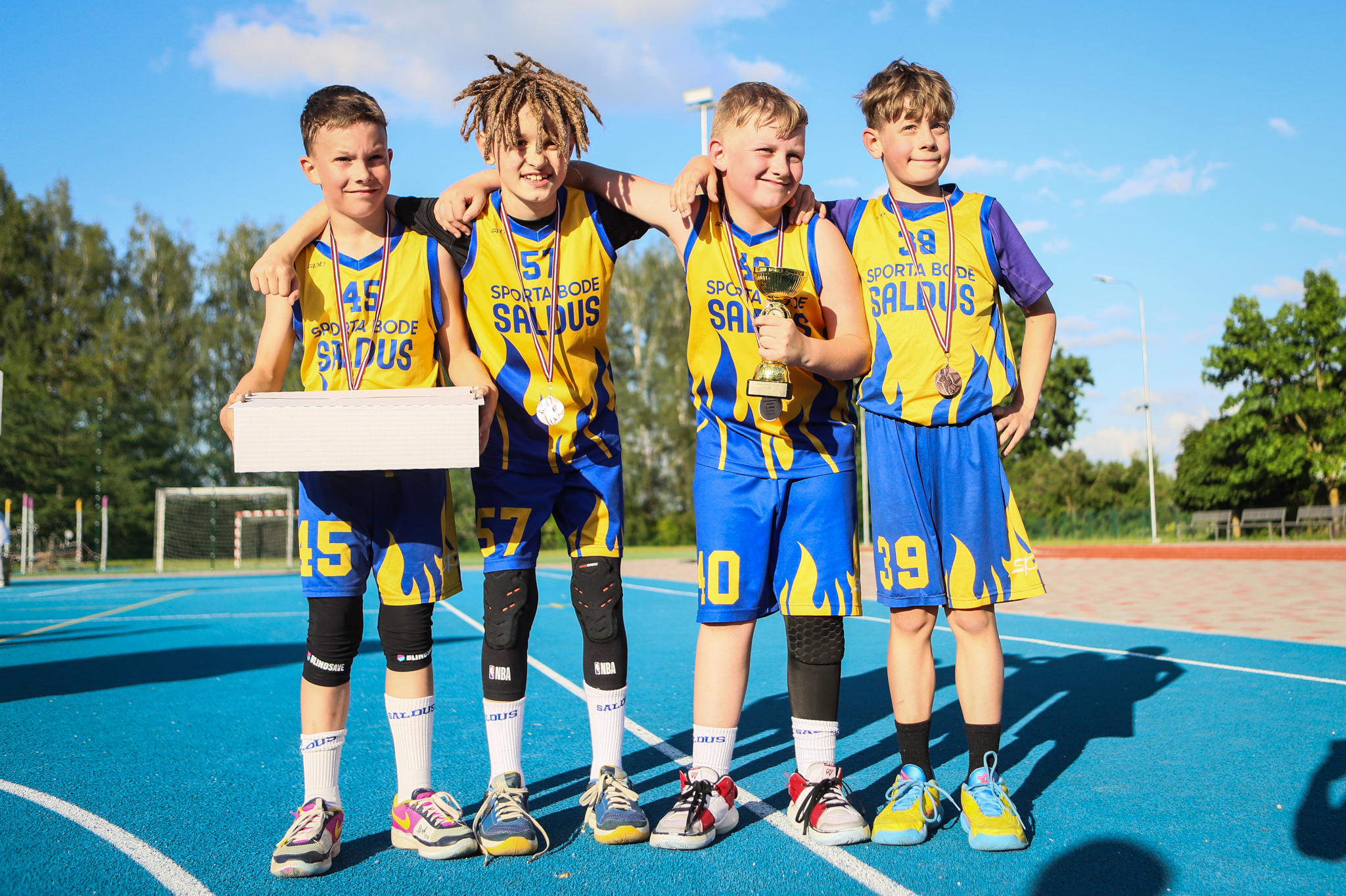 puiši spēlē basketbola uz zila seguma sporta laukumā
