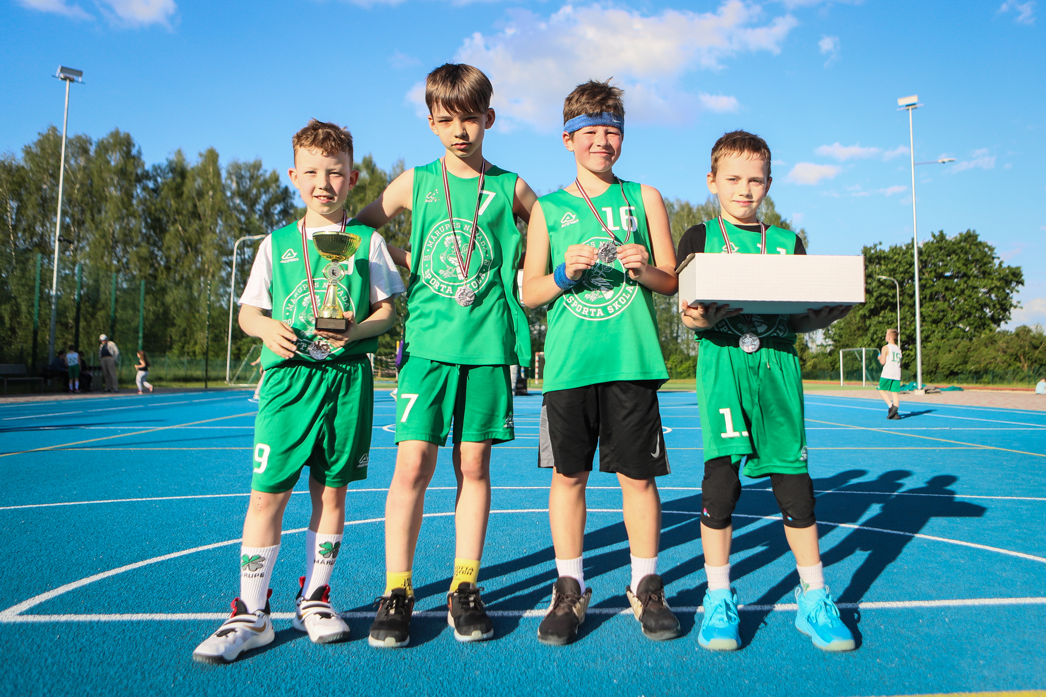puiši spēlē basketbola uz zila seguma sporta laukumā