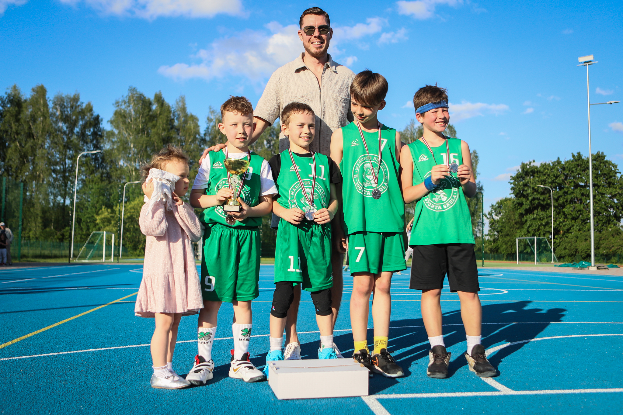 puiši spēlē basketbola uz zila seguma sporta laukumā