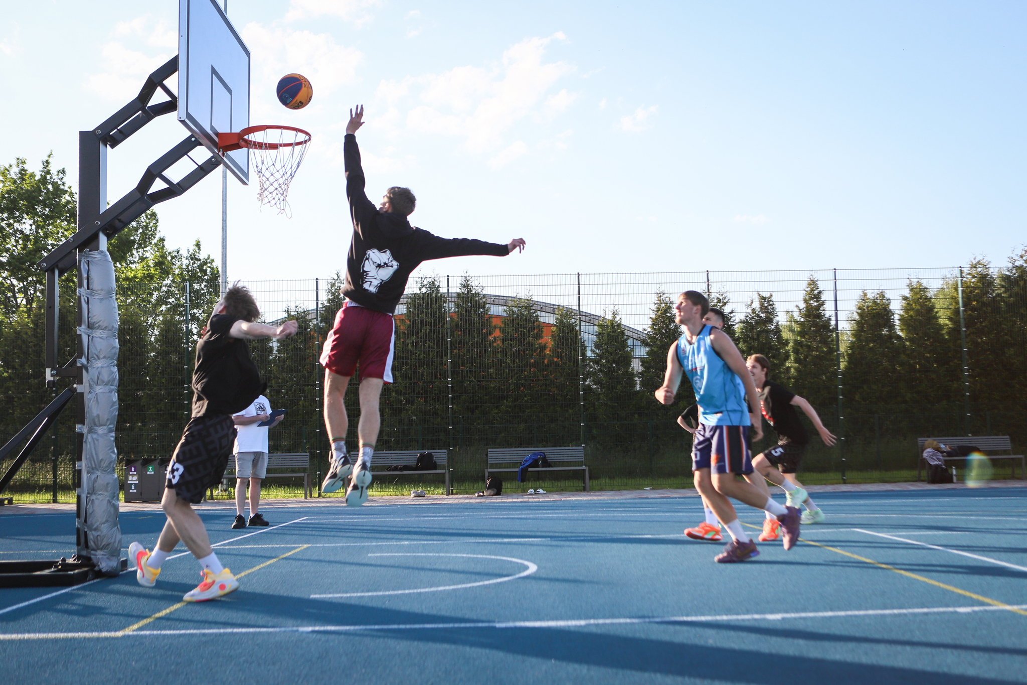 puiši spēlē basketbola uz zila seguma sporta laukumā