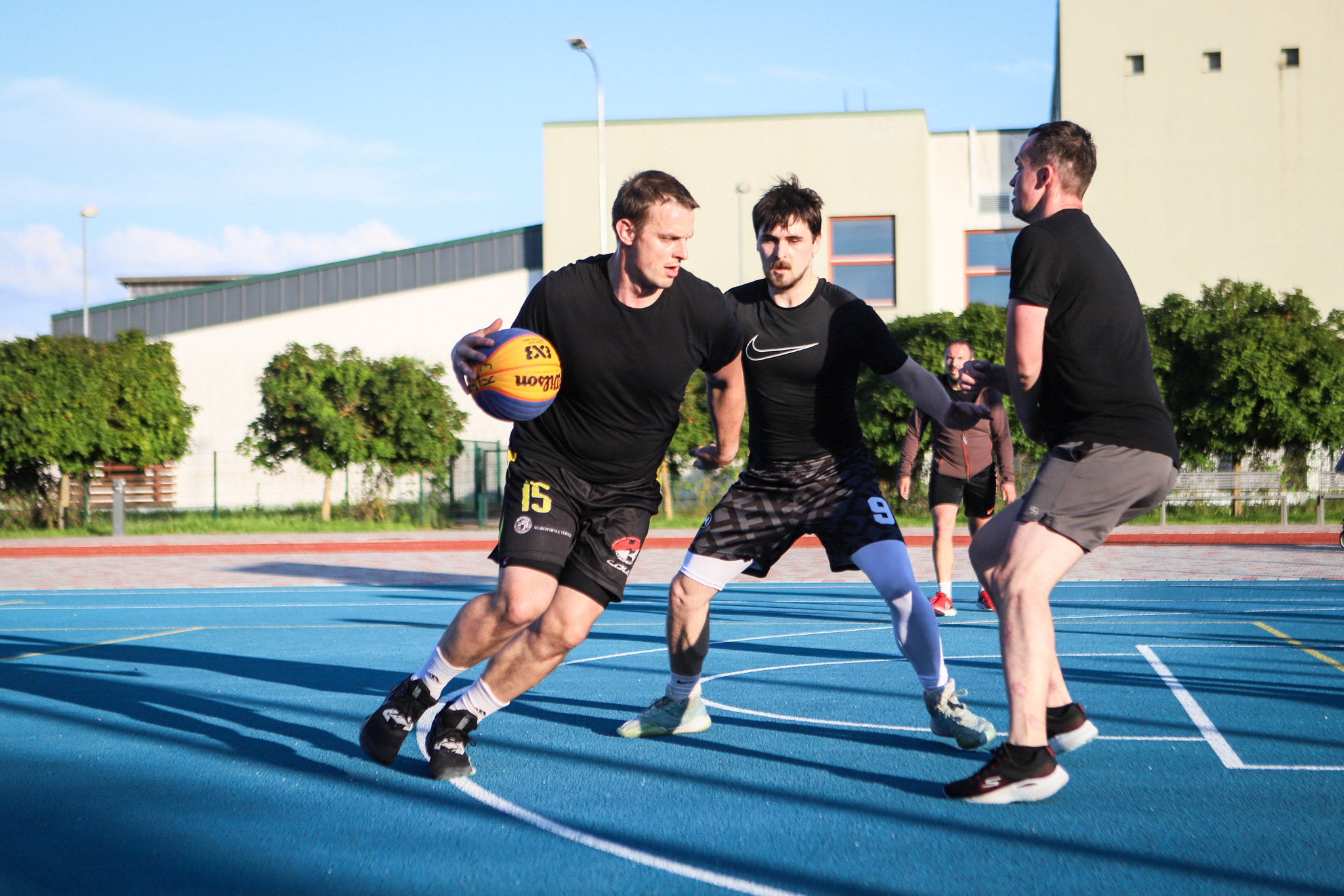 puiši spēlē basketbola uz zila seguma sporta laukumā