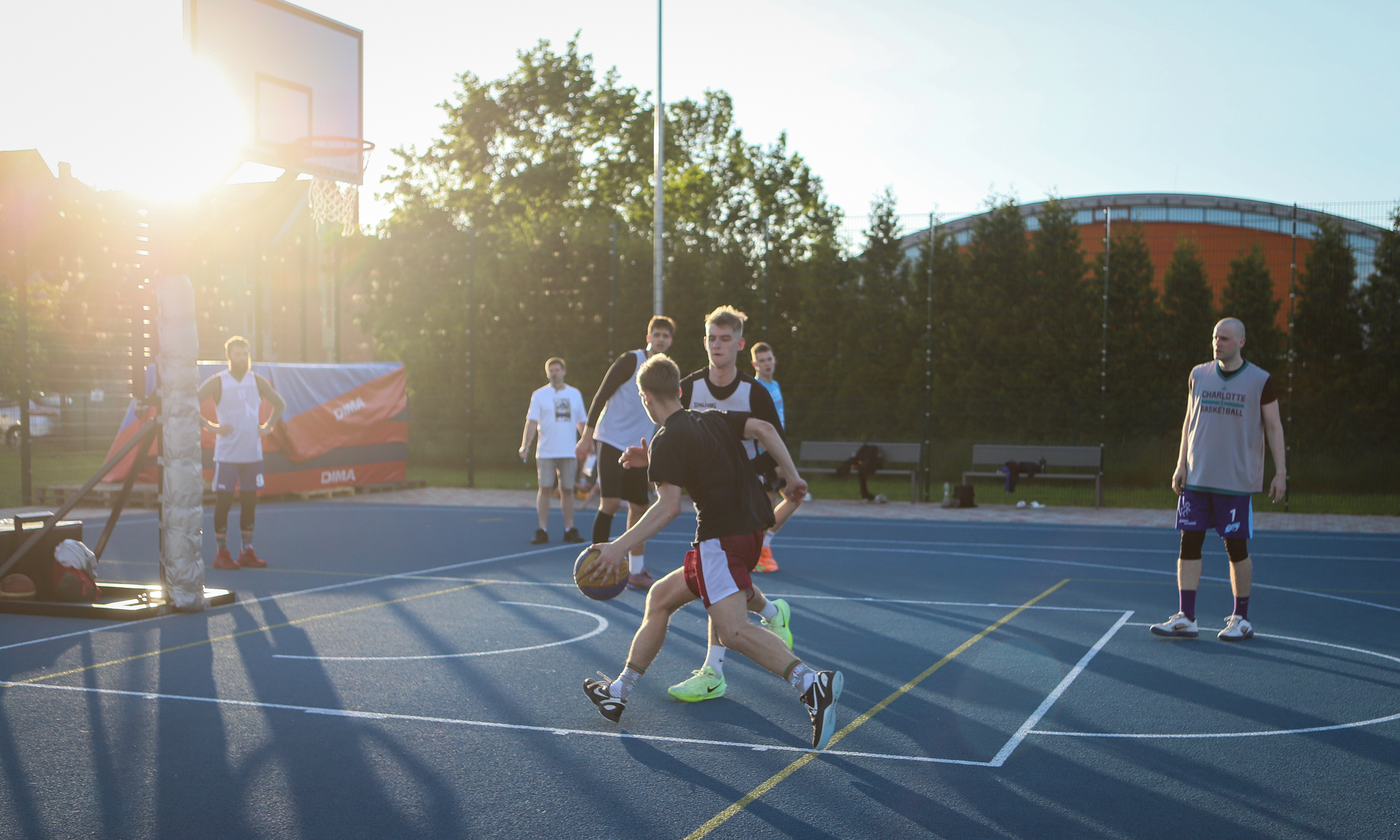 puiši spēlē basketbola uz zila seguma sporta laukumā