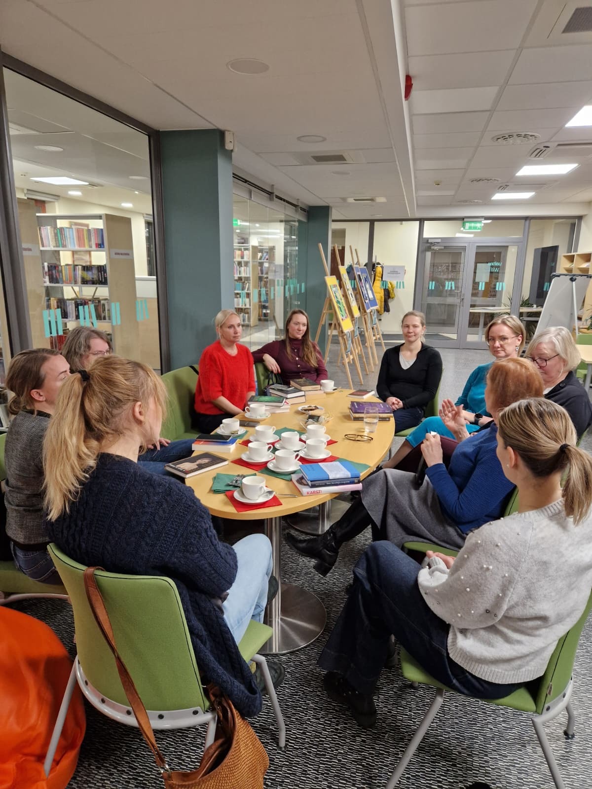 cilvēku grupa sēž ap galdu pie grāmatām