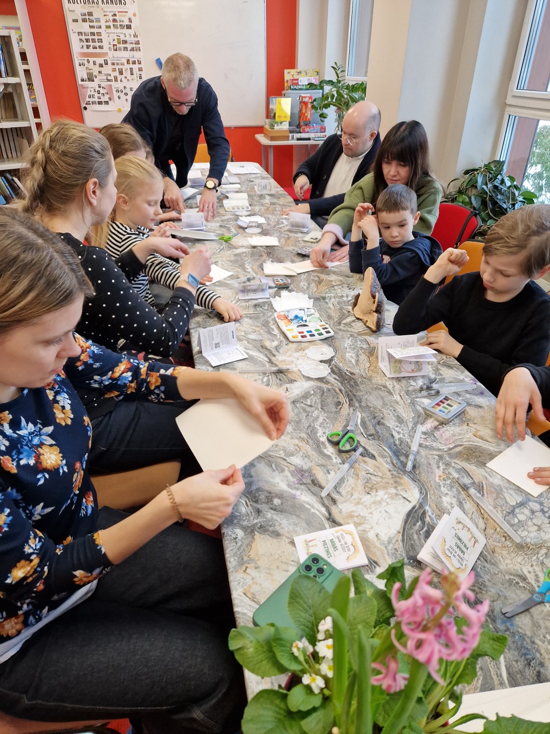 Mirklis no dabas piezīmju darbnīcām bibliotēkā - bērni kopā ar vecākiem darbojas pie liela galda