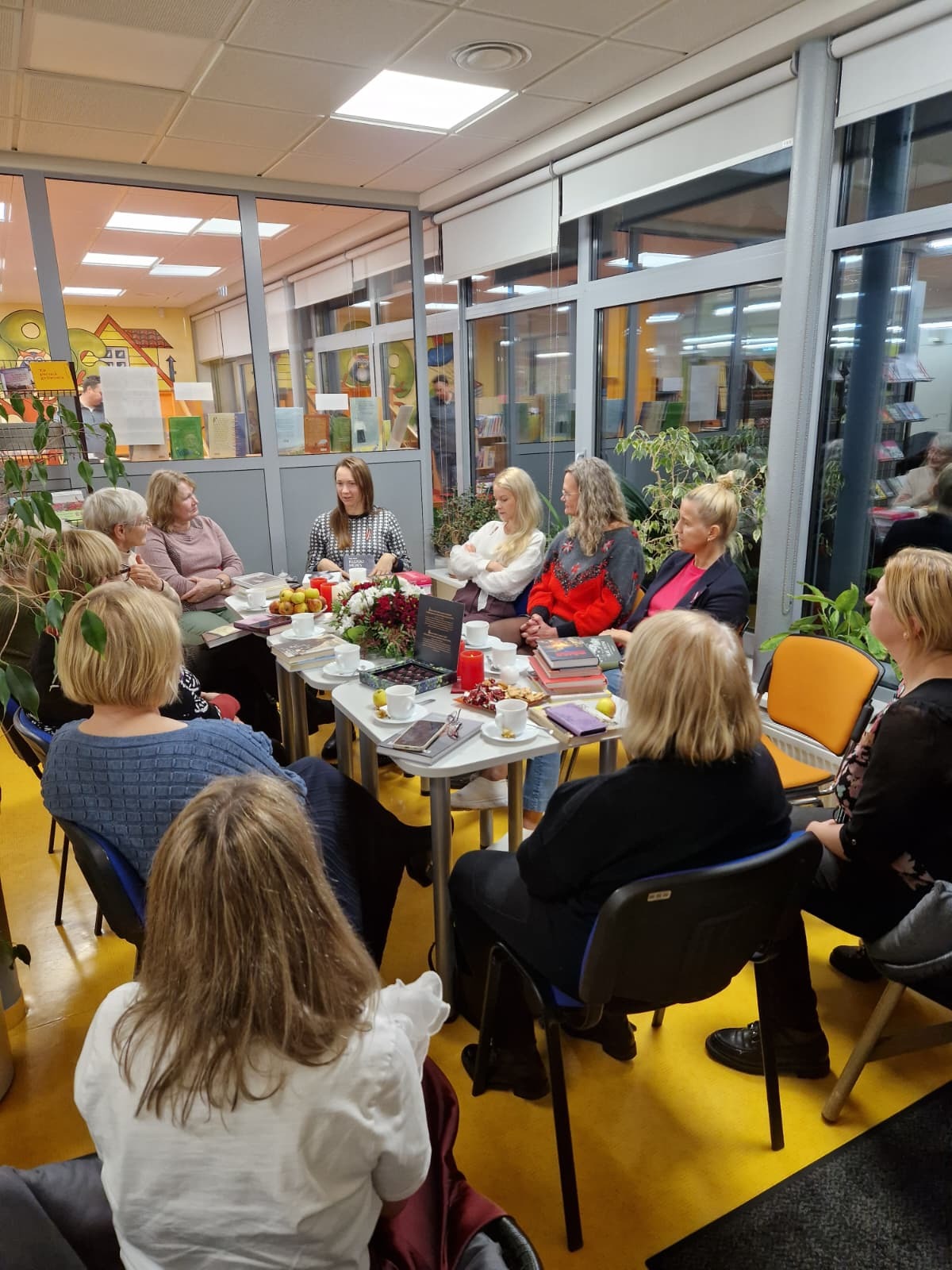 Cilvēku pulks pie galda ar grāmatām