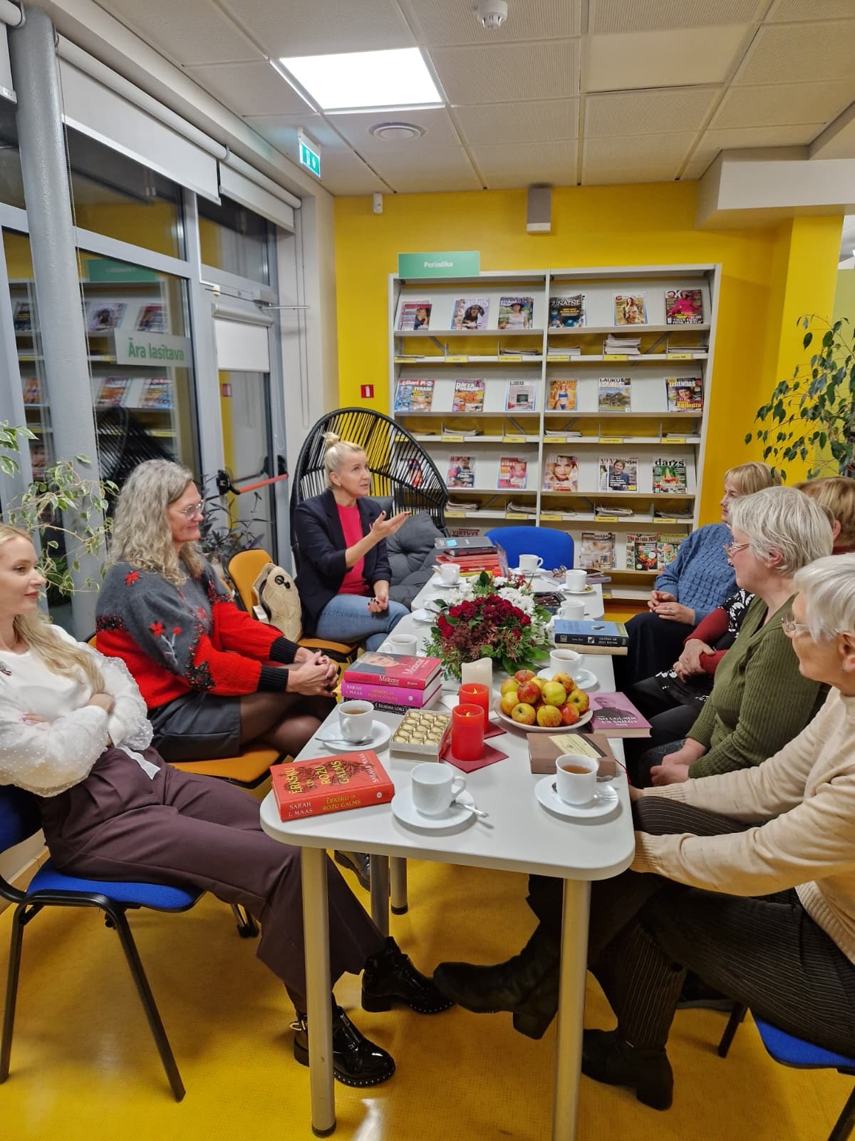 Cilvēku pulks pie galda ar grāmatām