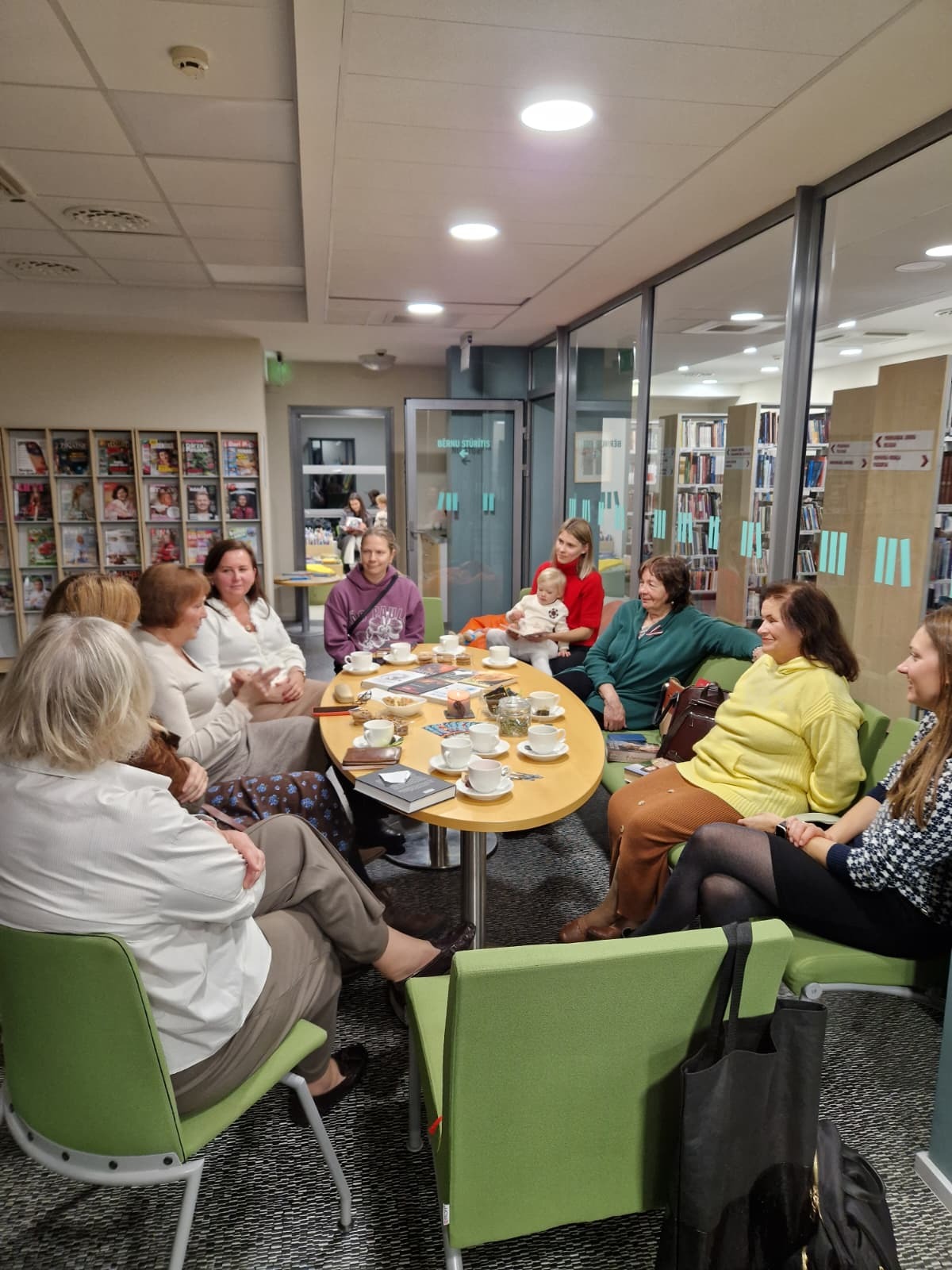 Grāmatu klubiņa dalībnieki ap galdu