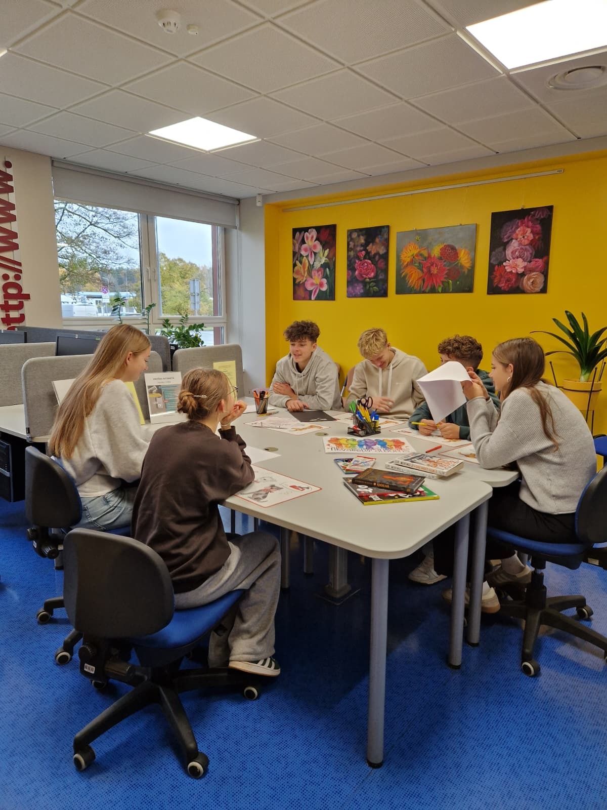 Jauniešu grupa pie galda radošās nodarbības laikā