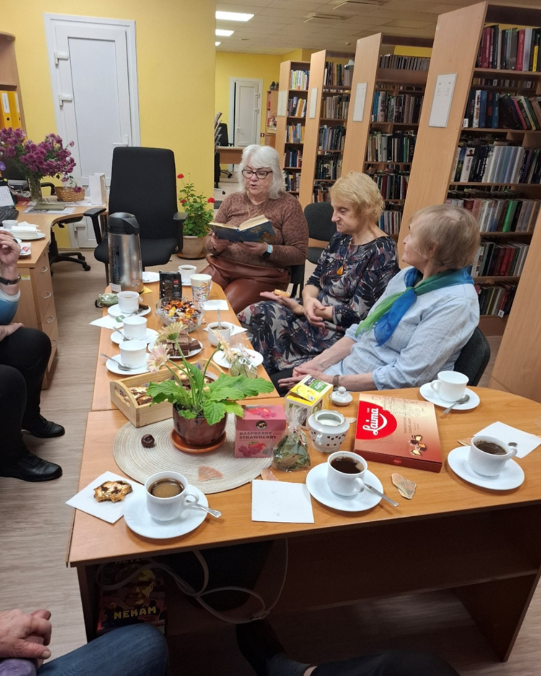 Grāmatu klubiņa biedru tikšanās pie galda ar tēju un grāmatām