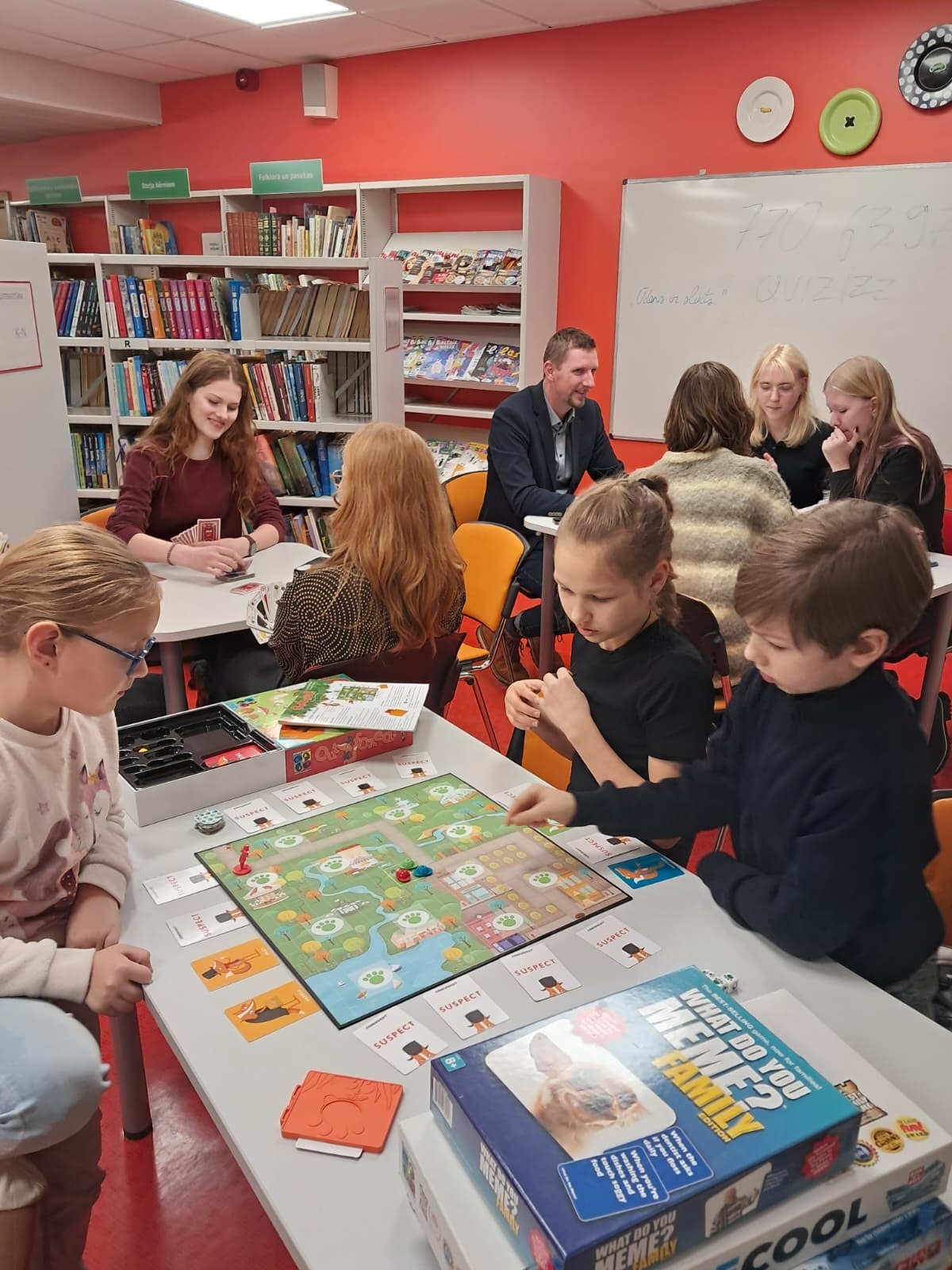 Cilvēku grupas kopbilde pie galda spēlējot spēles