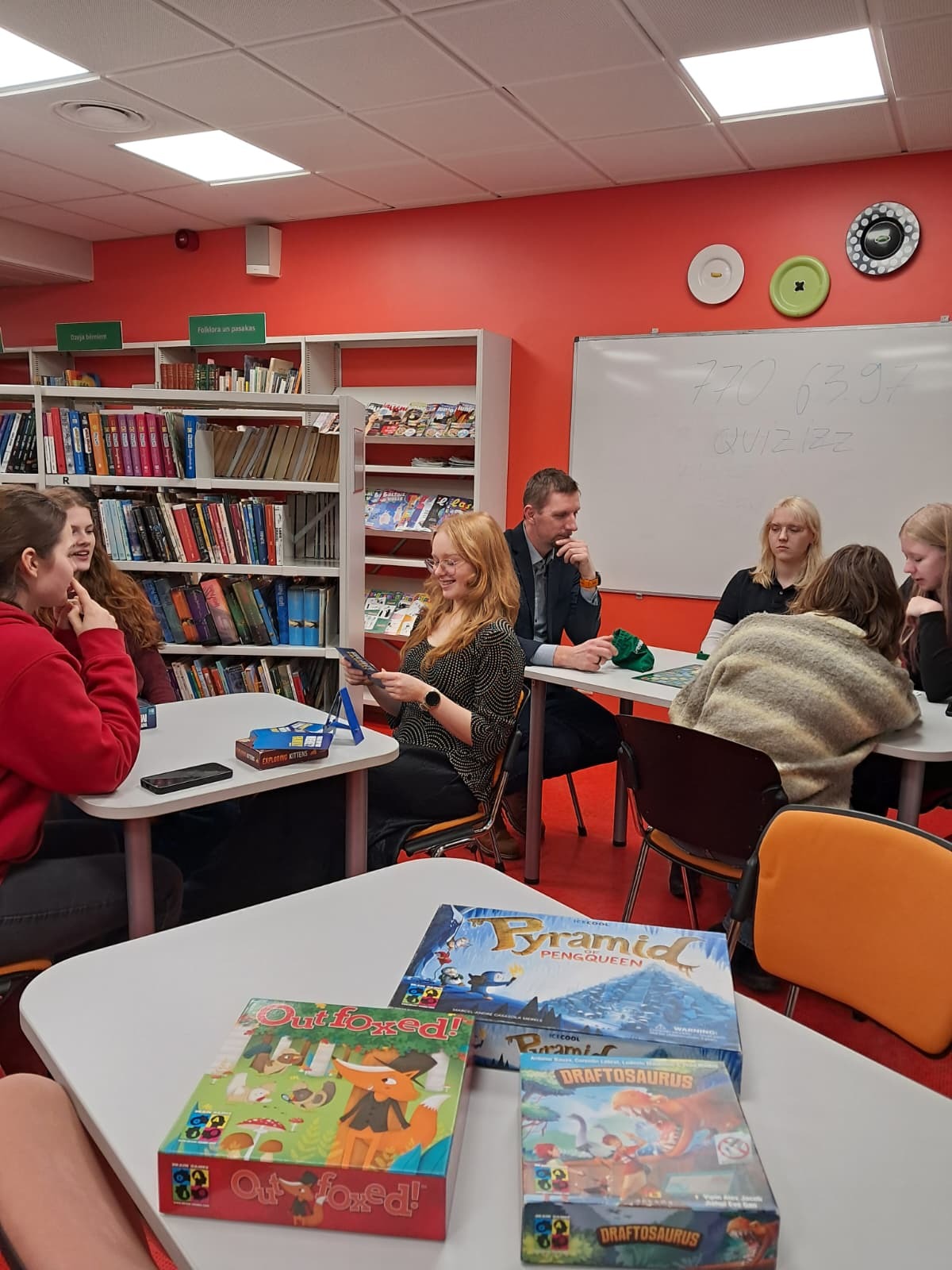 Cilvēku grupas kopbilde pie galda spēlējot spēles