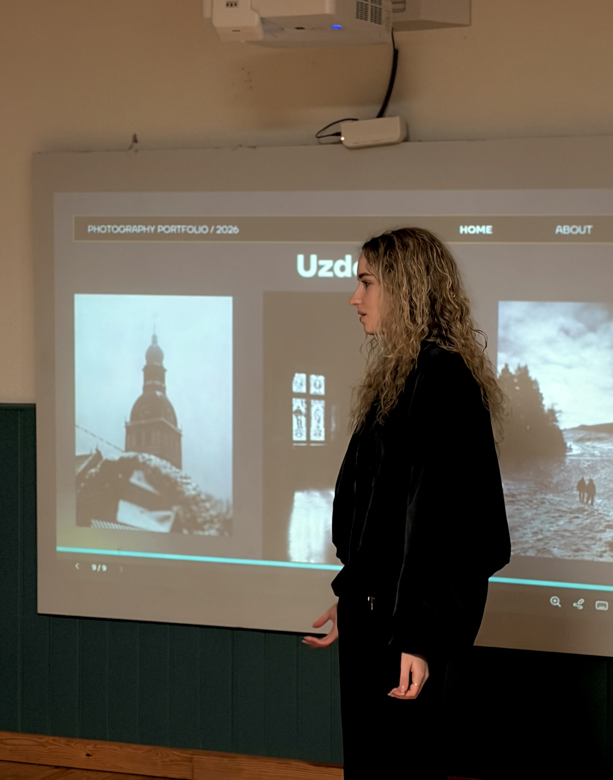 lektore auditorijas priekšā pie izgaismotas tāfeles