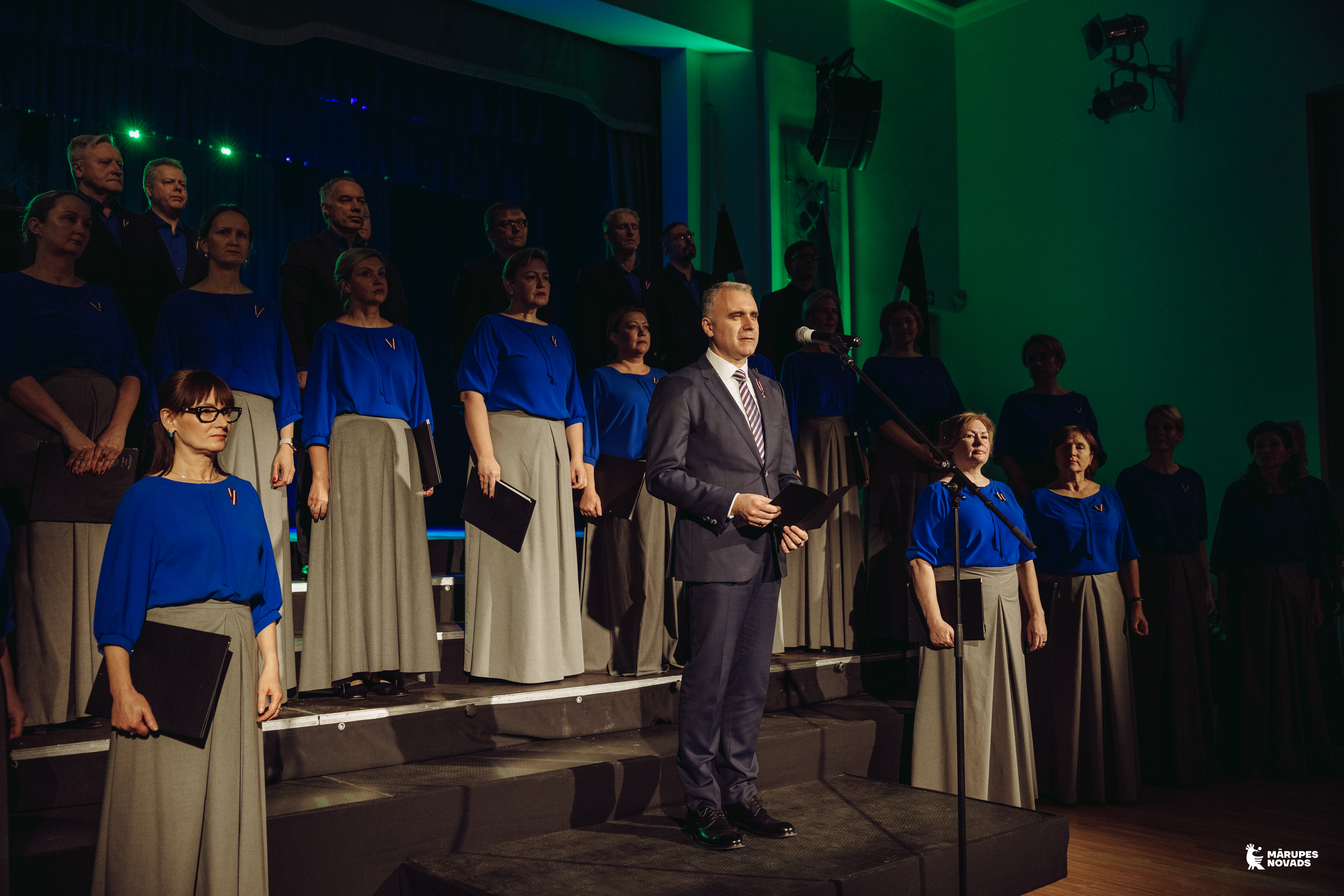 Vīrietis saka uzrunu mikrofonā