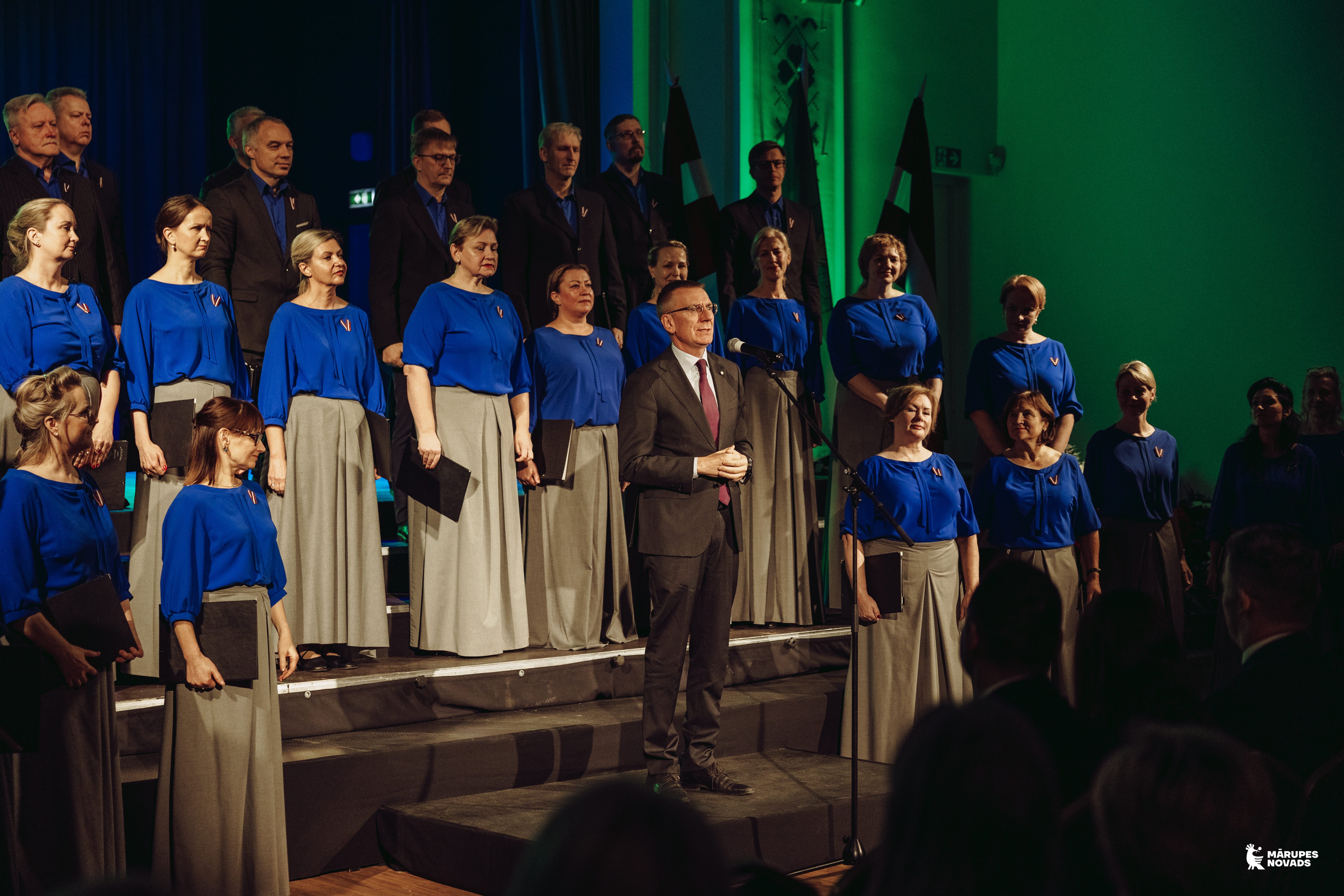 Vīrietis saka uzrunu mikrofonā