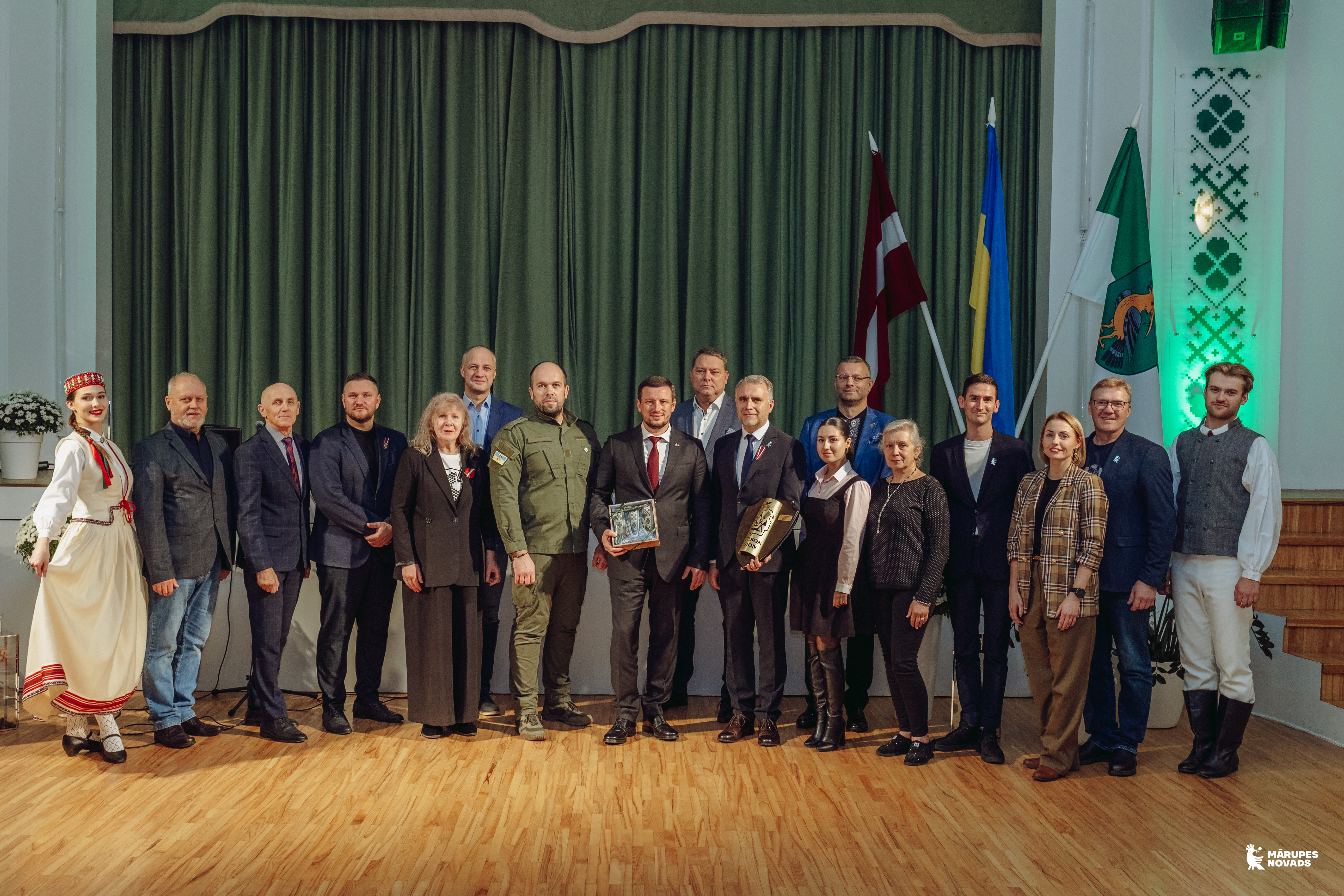 Cilvēku pulka kopbilde pie zaļa fona