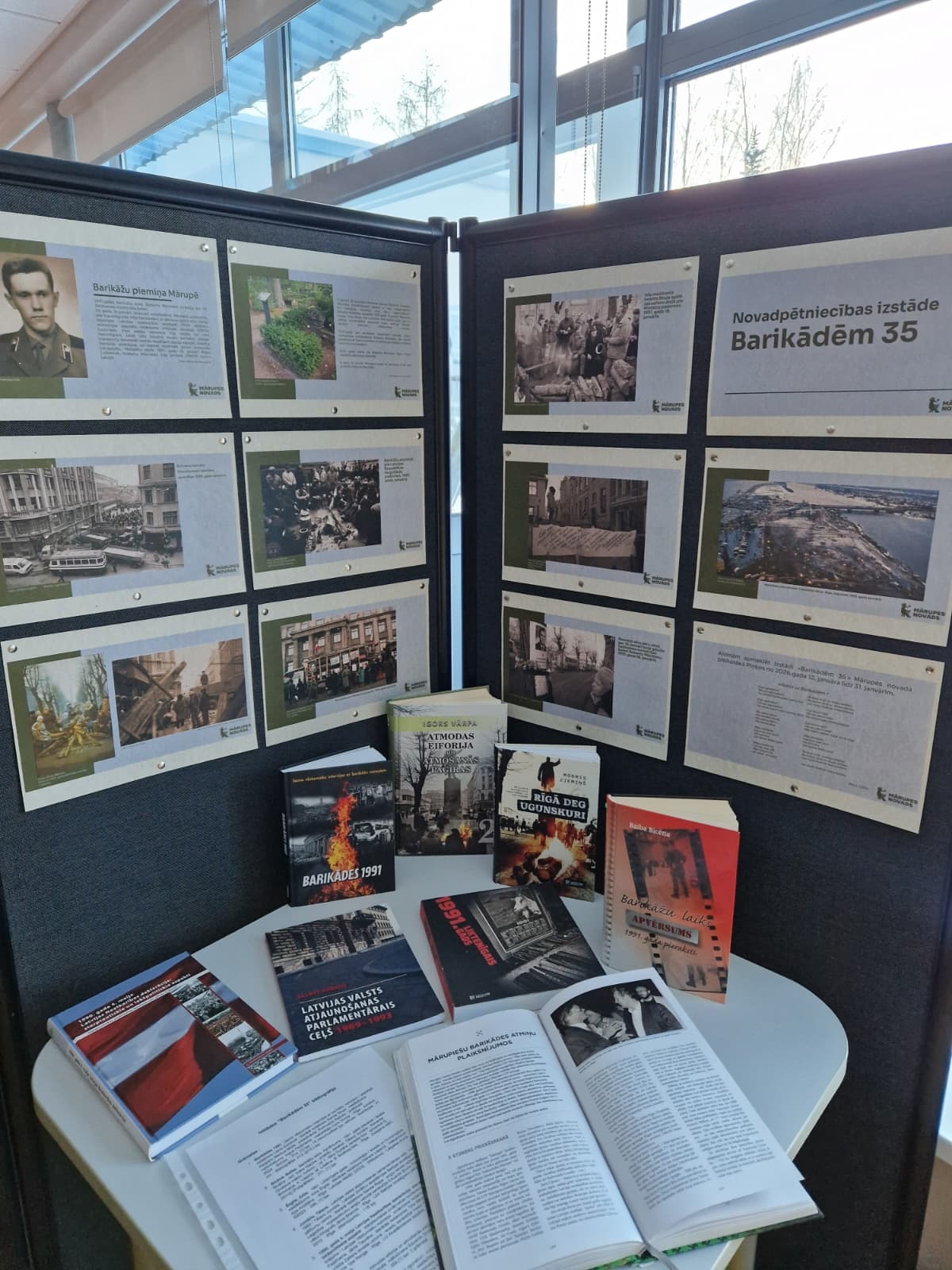 tumšs fons ar izstādes plakātiem