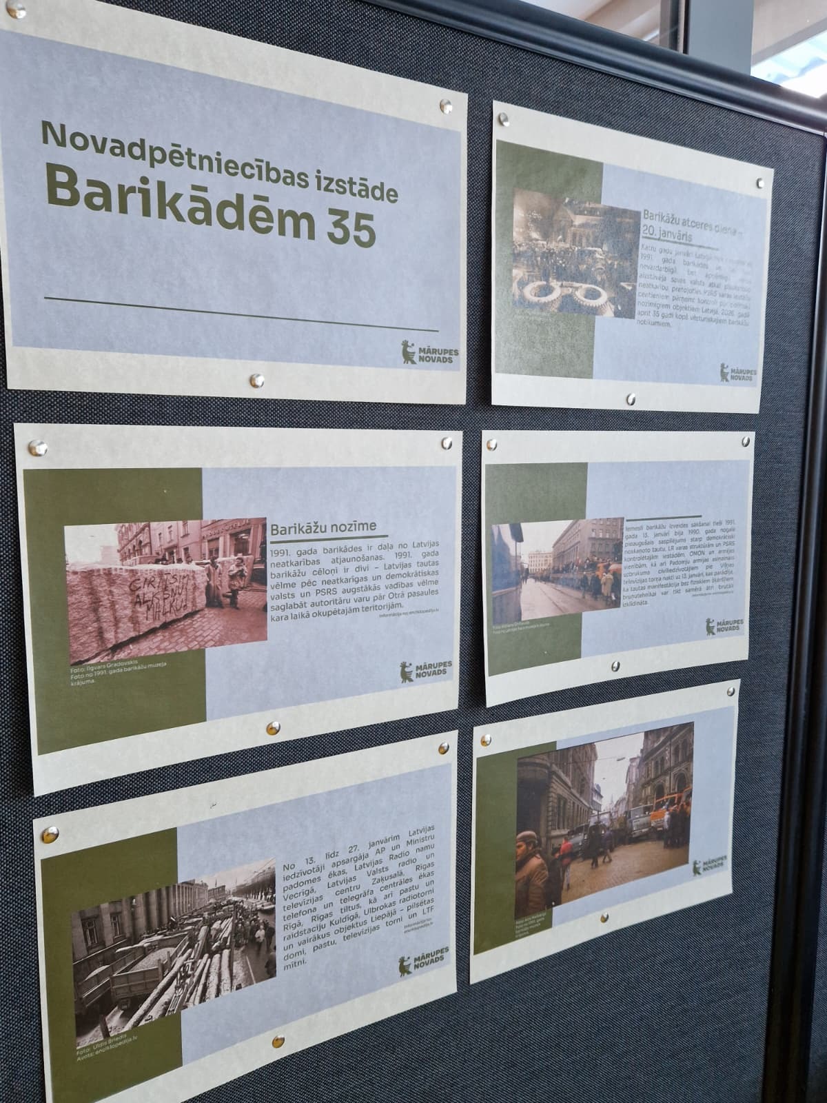 tumšs fons ar izstādes plakātiem