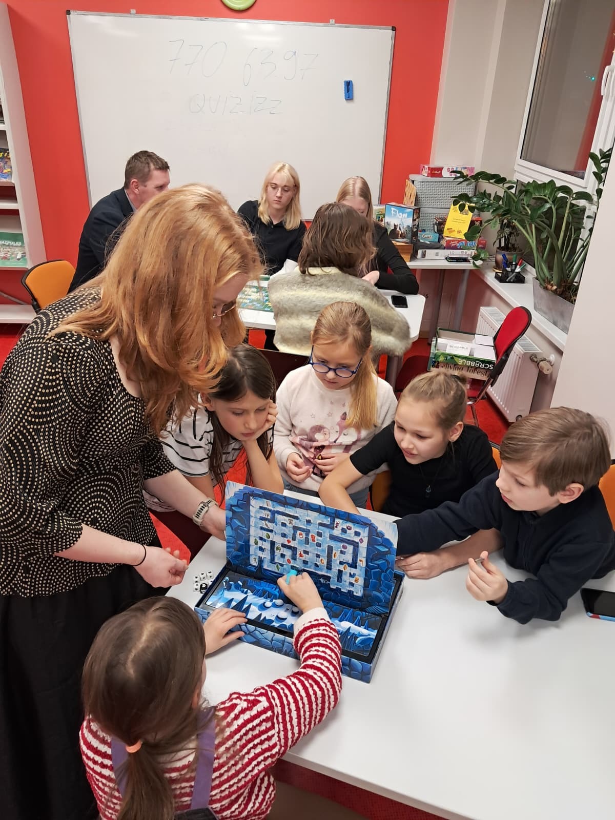 Cilvēku grupas kopbilde pie galda spēlējot spēles