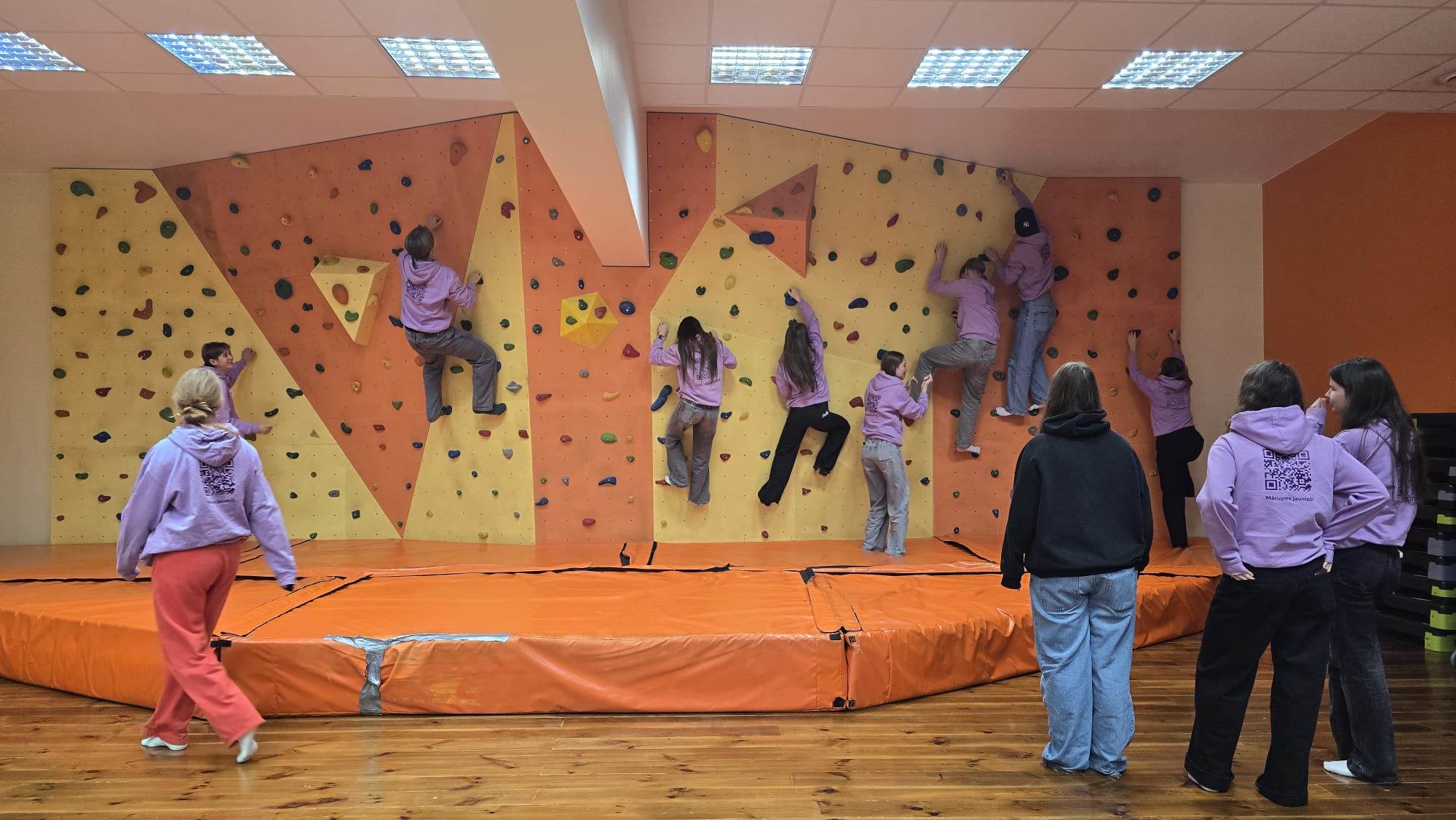 Jaunieši pie krāsainas alpīnisma sienas