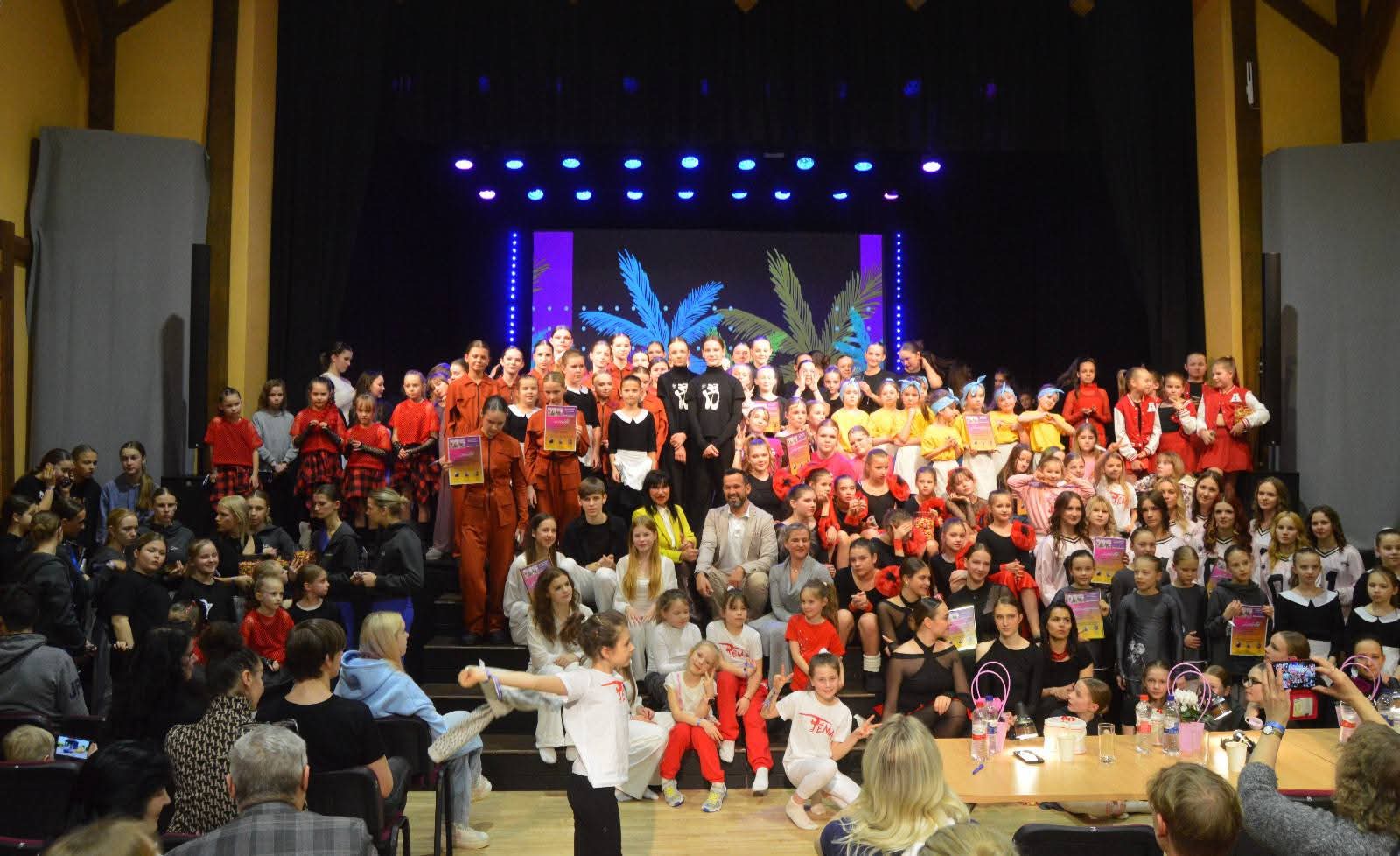 kopbilde ar vairāk nekā simts bērniem un jauniešiem, kuri piedalās deju konkursā