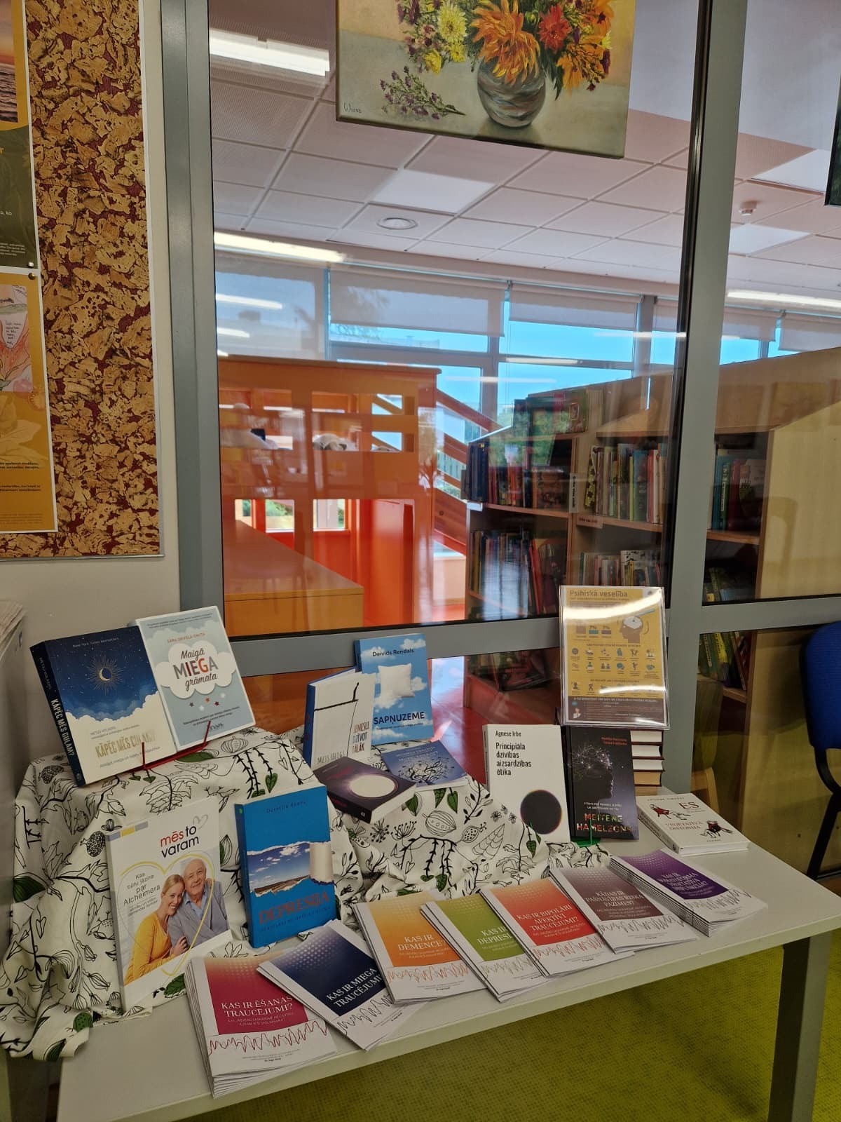 Grāmatas un bukleti izstādē uz galda gaišā telpā