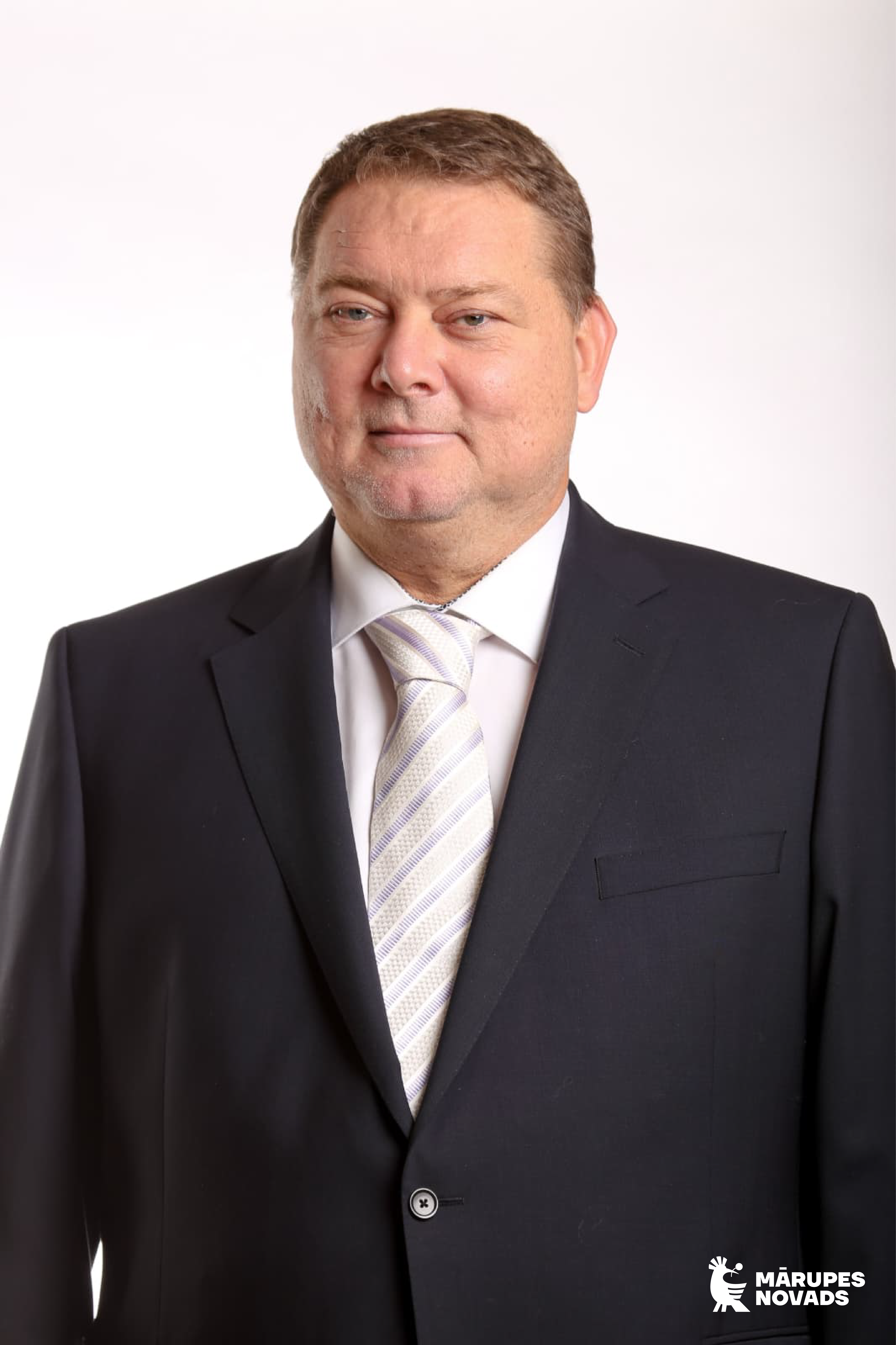 Vīrieša profils tumšās drēbēs uz gaiša fona