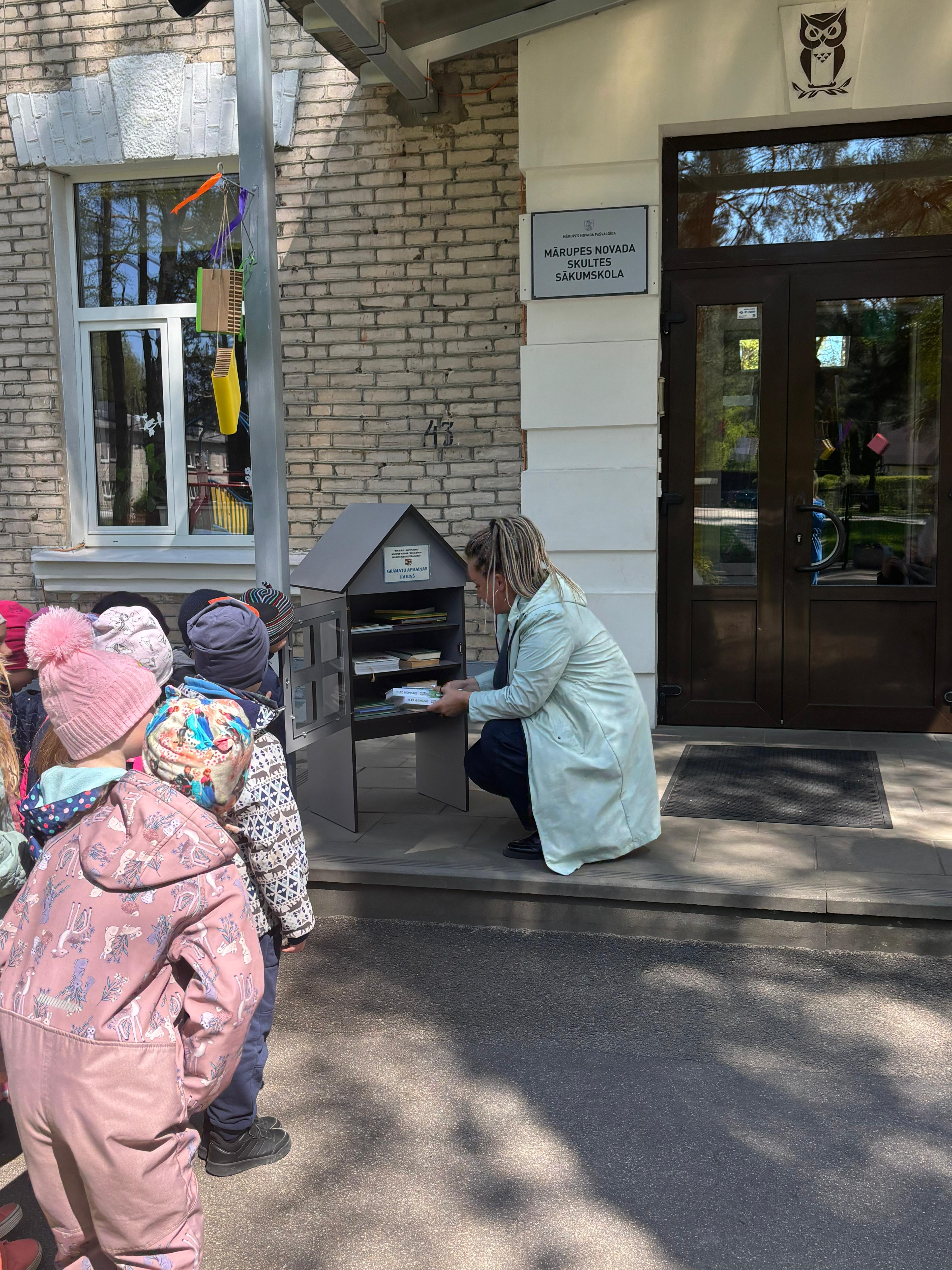 Sieviete ar grāmatu rokās sēž uz trepēm