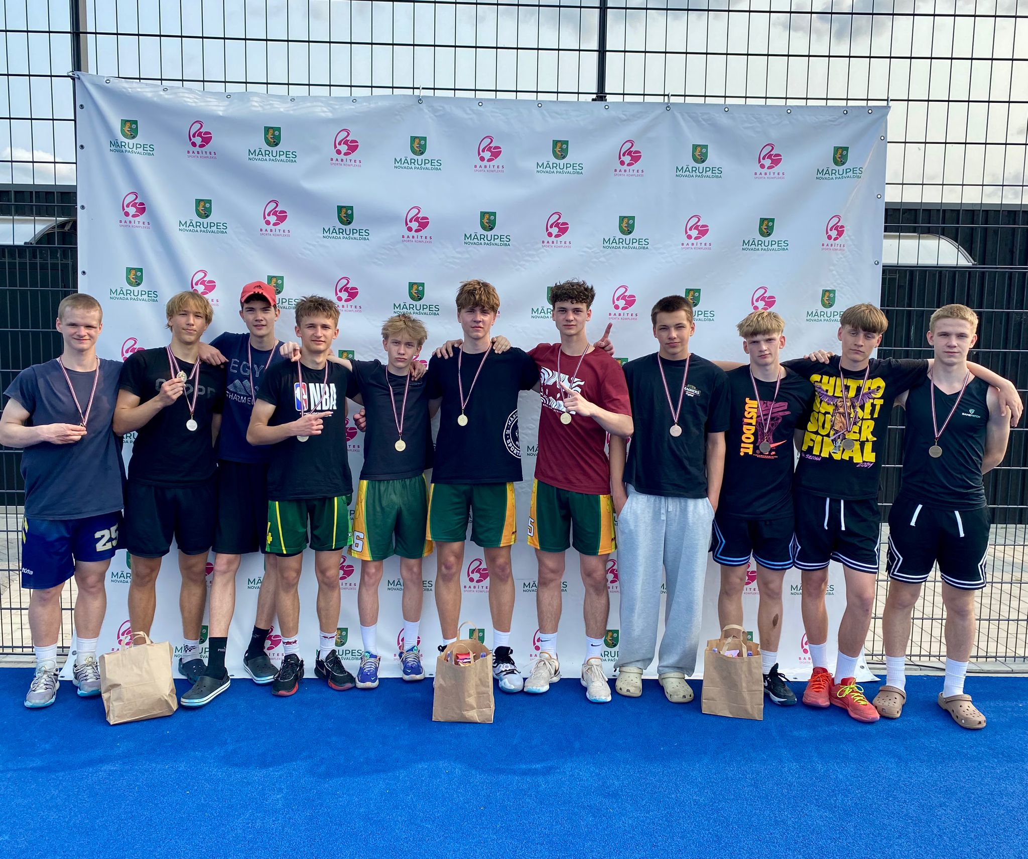 Pusaudži sporta tērpos stāv pie baltas foto sienas