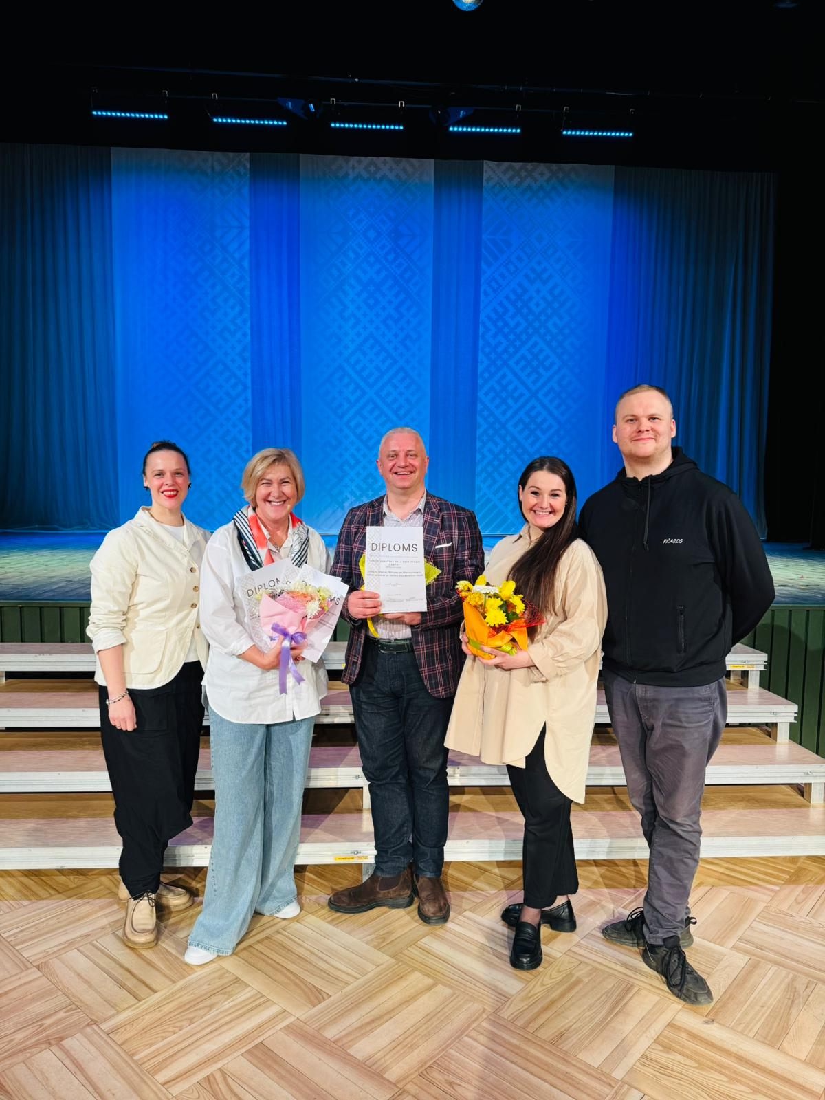 deju kolektīva vadītāji ar diplomiem pie skatuves