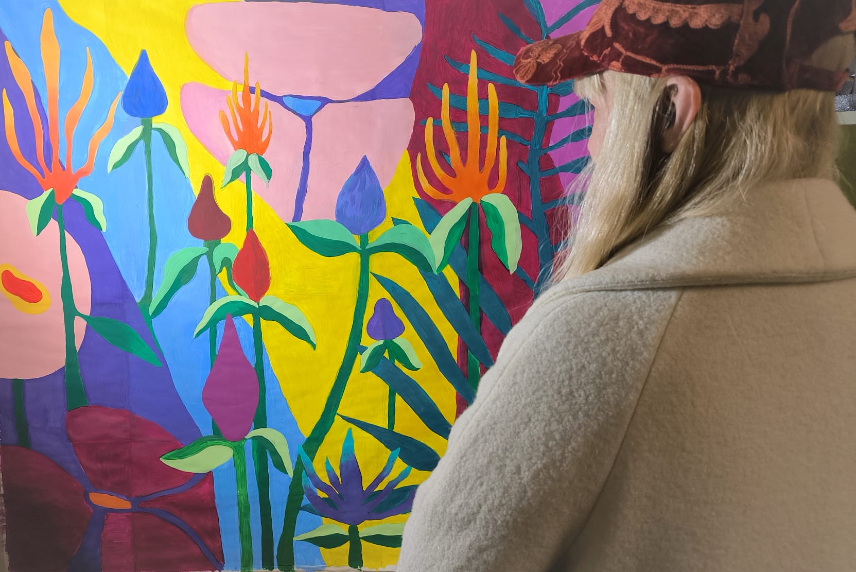 sieviete aplūko košu gleznu ar ziediem