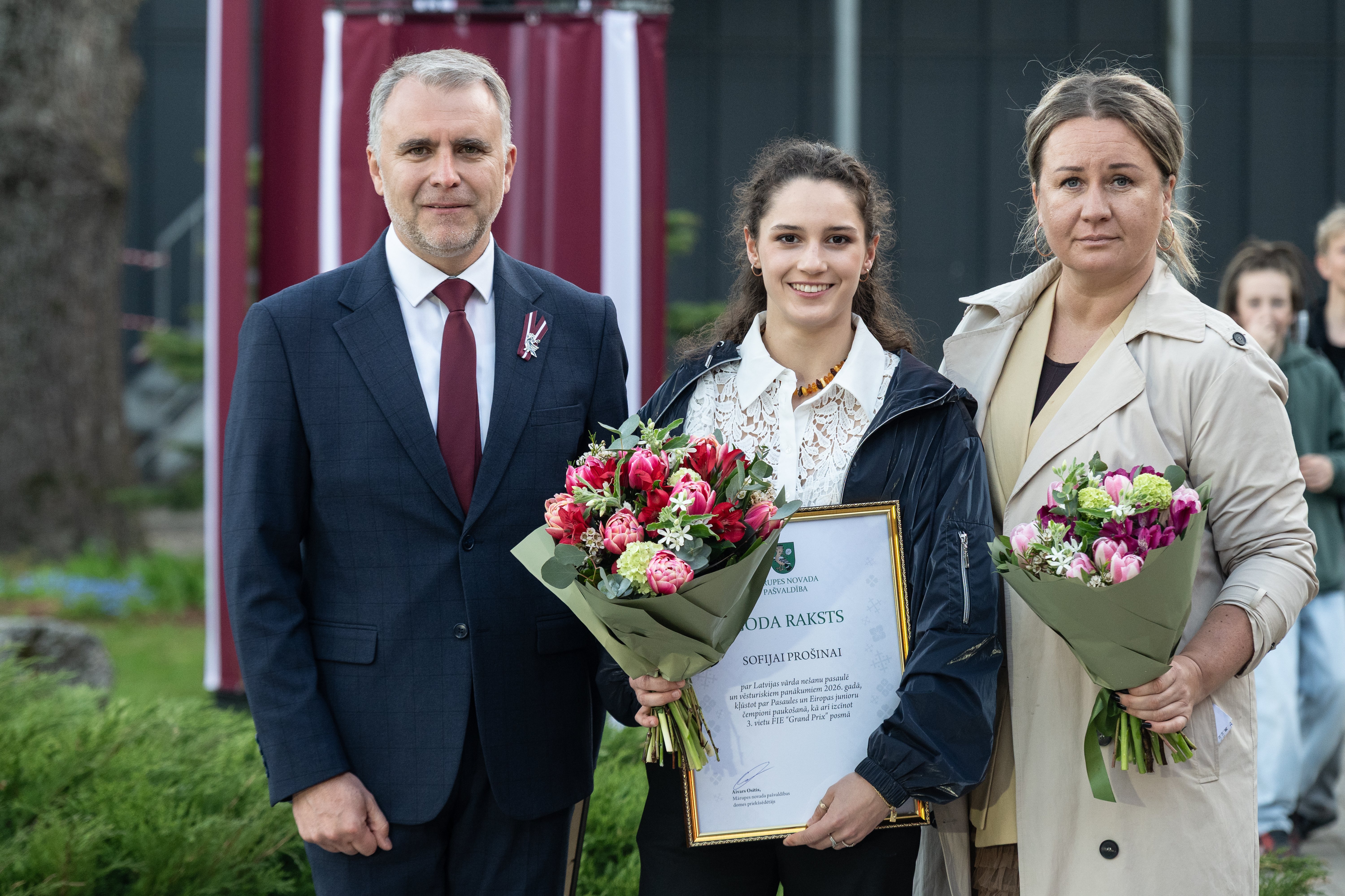 Aivars Osītis un Liene Šmite, pasniedz Goda rakstu Sofijai Prošinai