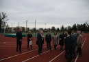 Sievietes un vīrieši apskata skolas sporta stadionu, stāv uz skrejceliņa