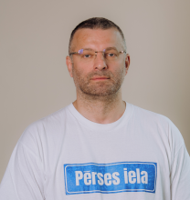 Vīrietis uzvalkā uz gaiša fona
